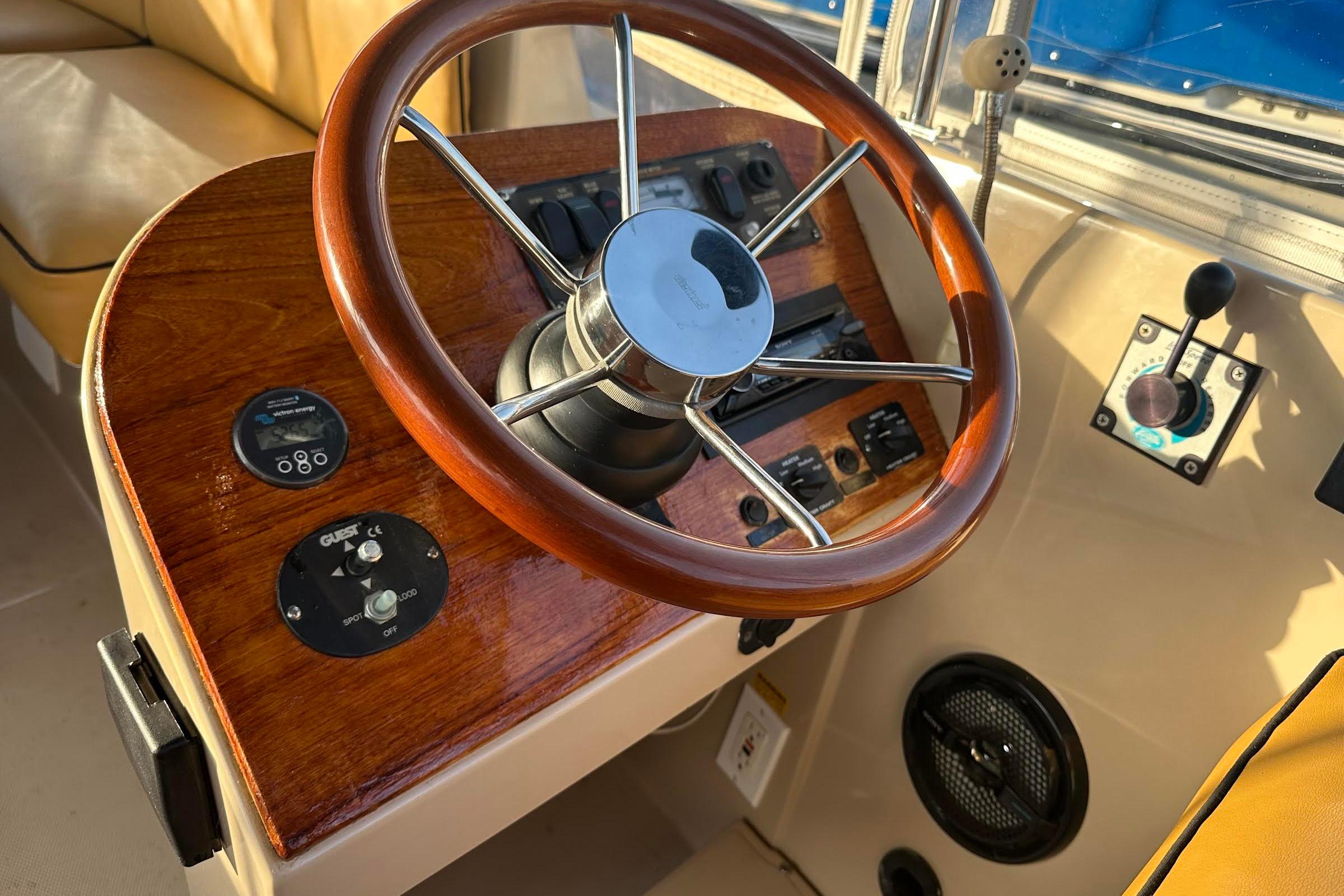 Steering wheel and controls of a 2007 Duffy 22 Electric boat, featuring wood accents.