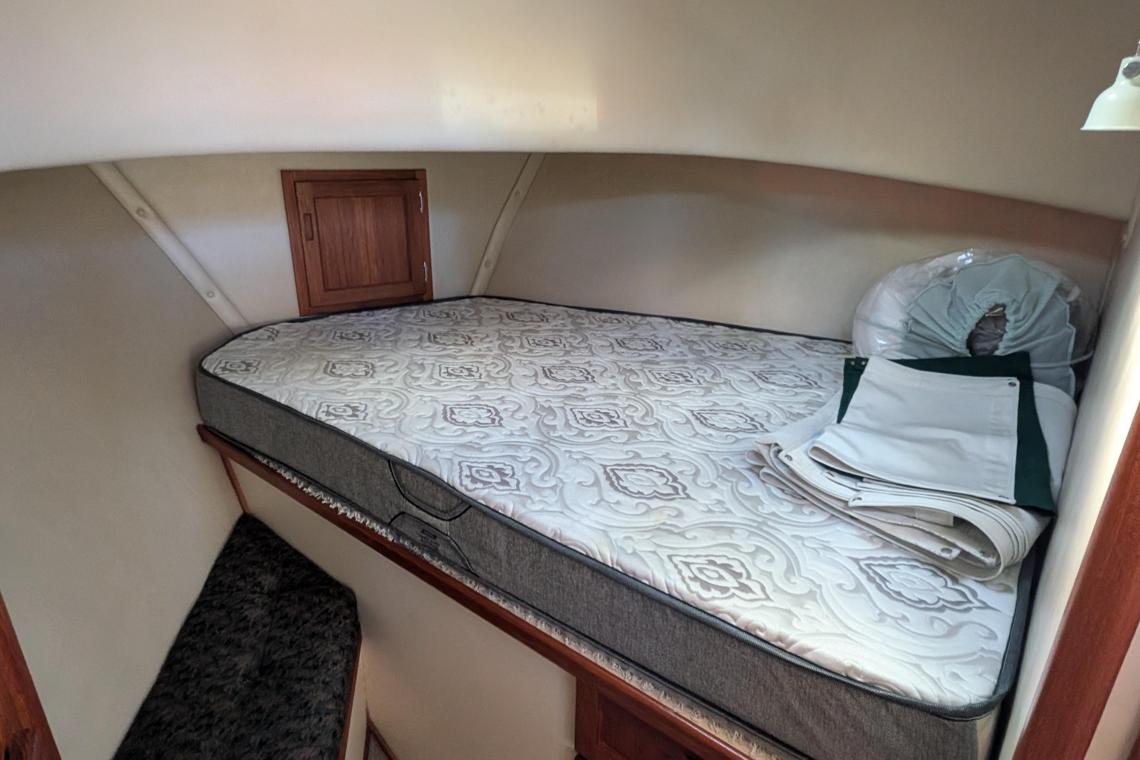 Cozy cabin interior of 1998 Nordic Tug 32 with mattress and storage.