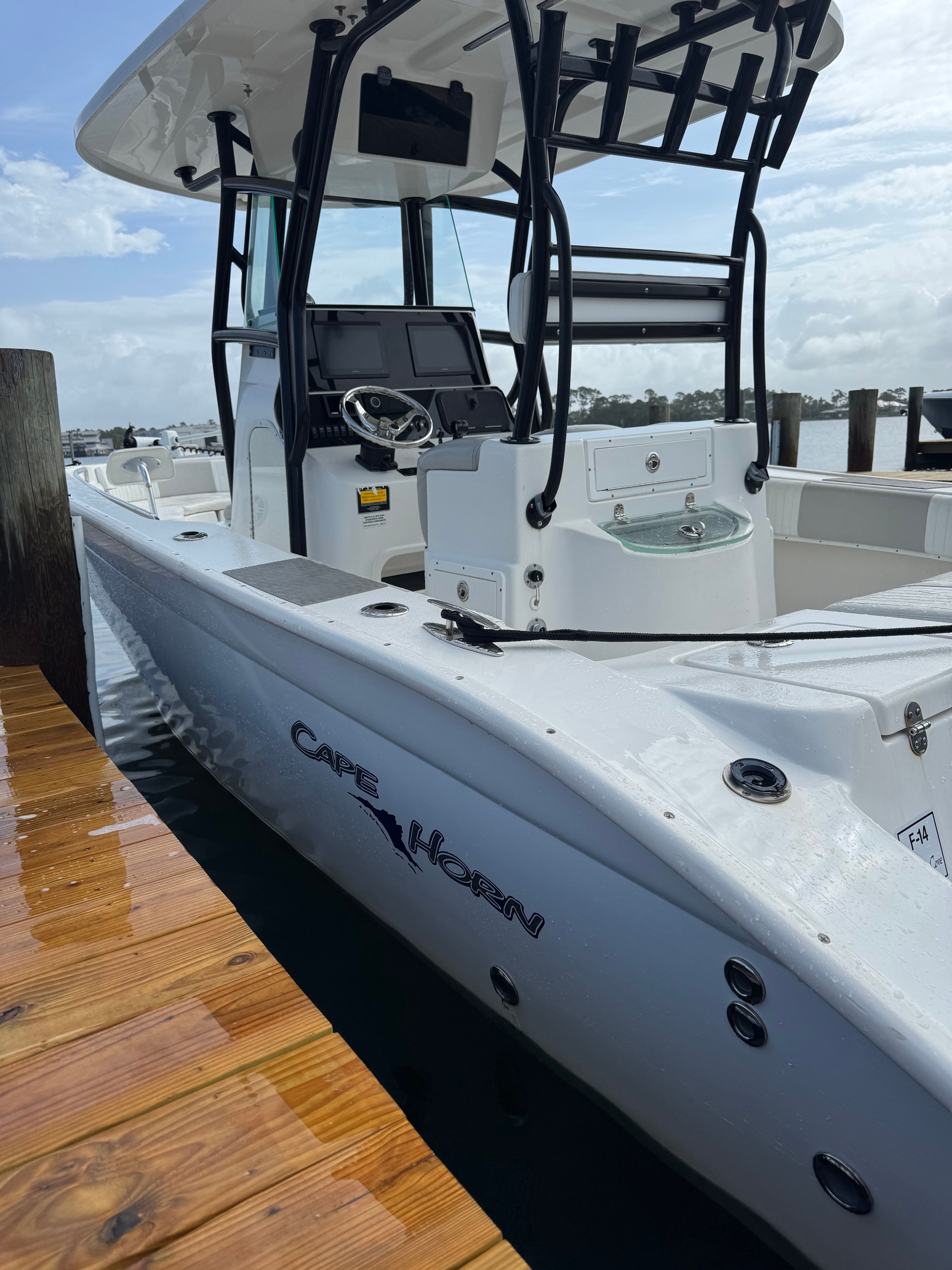 A white 2014 Cape Horn 24XS boat is docked at a wooden pier.