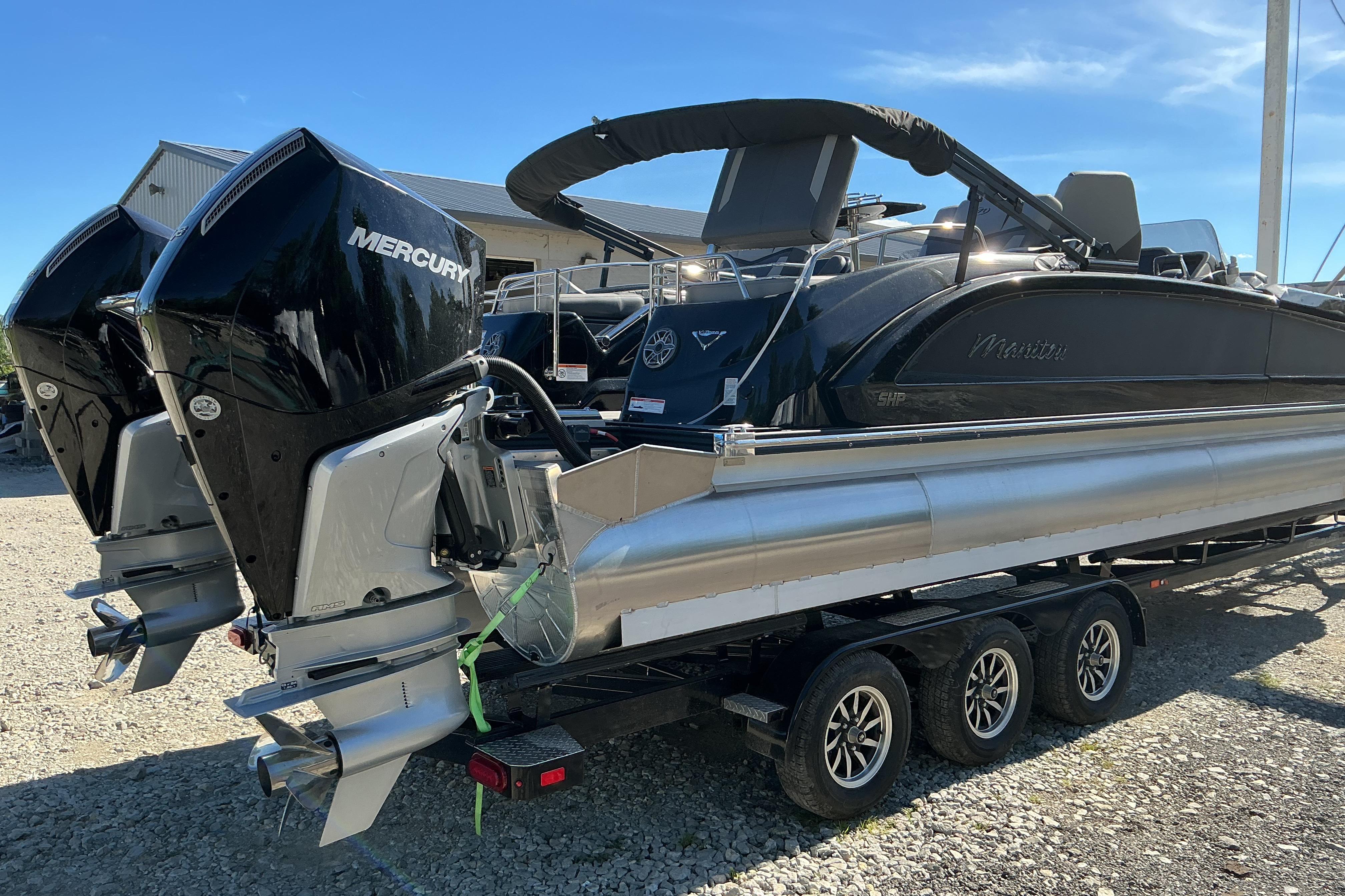 2024 Manitou 25 X-Plode XT SRS pontoon boat with dual Mercury engines on a trailer.