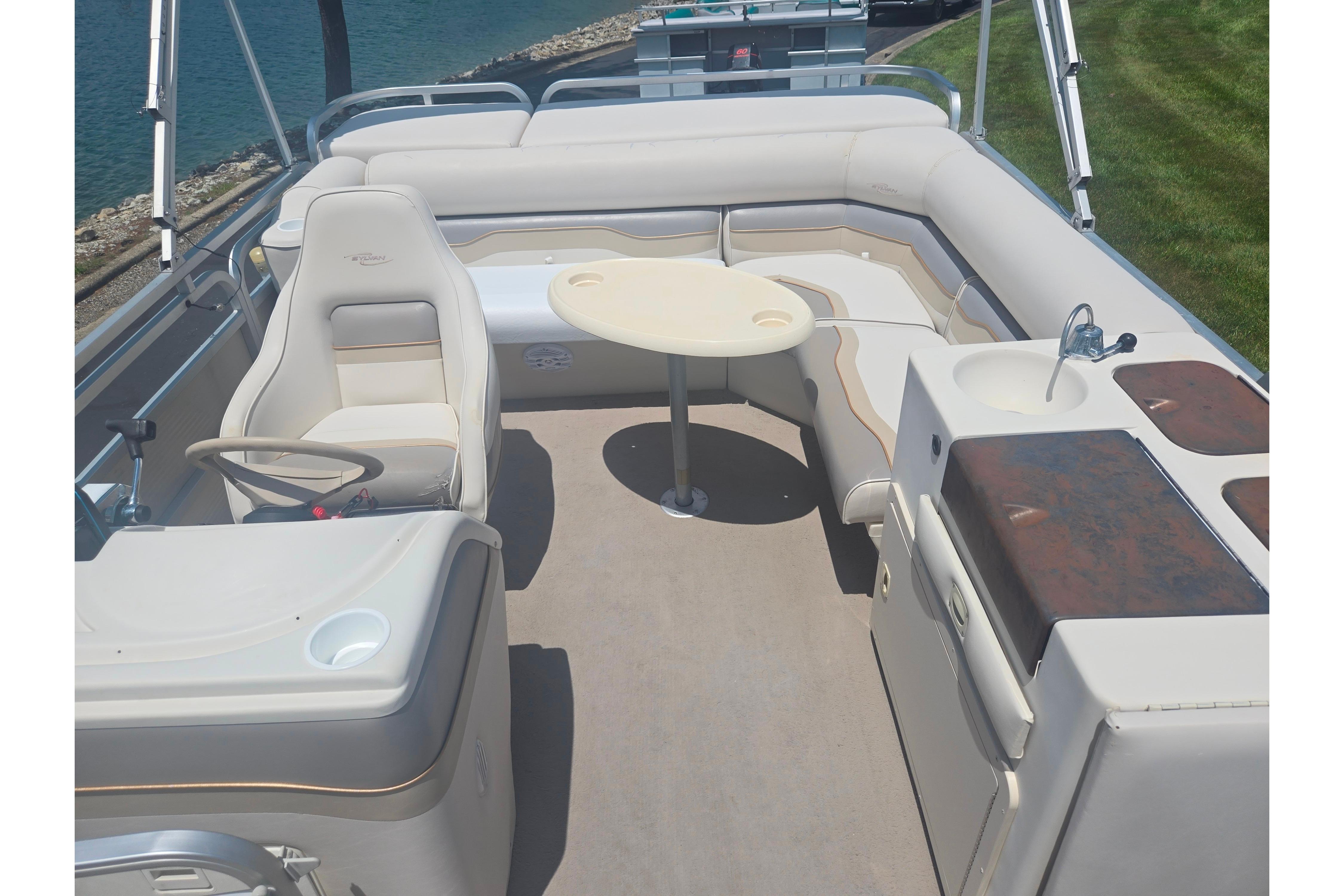 Interior of 2000 Sylvan 824 Elite Cruise boat with seating, table, and helm.