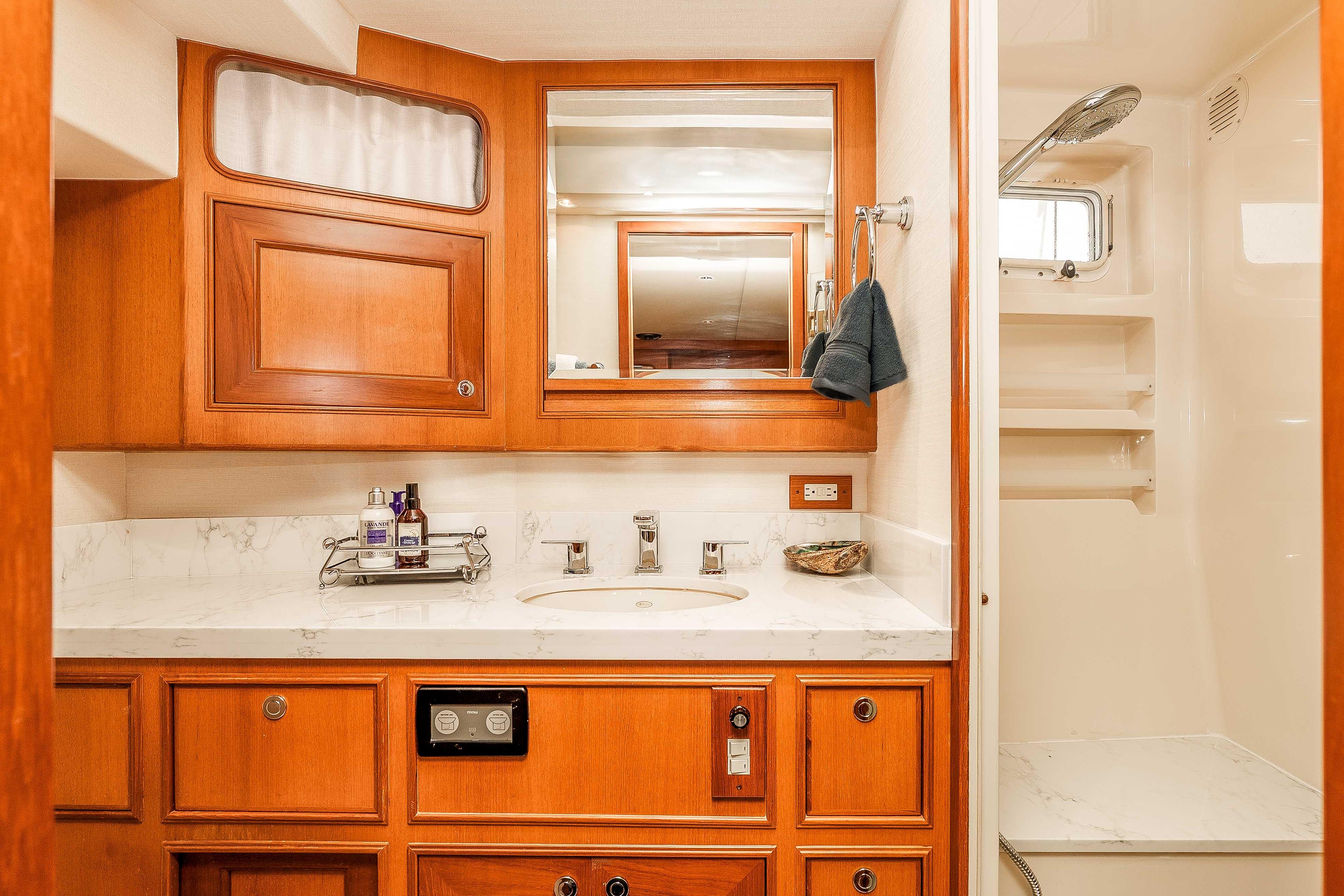 Luxurious bathroom in 2005 Offshore Yachts 54 Pilothouse with wood cabinetry and marble countertop.
