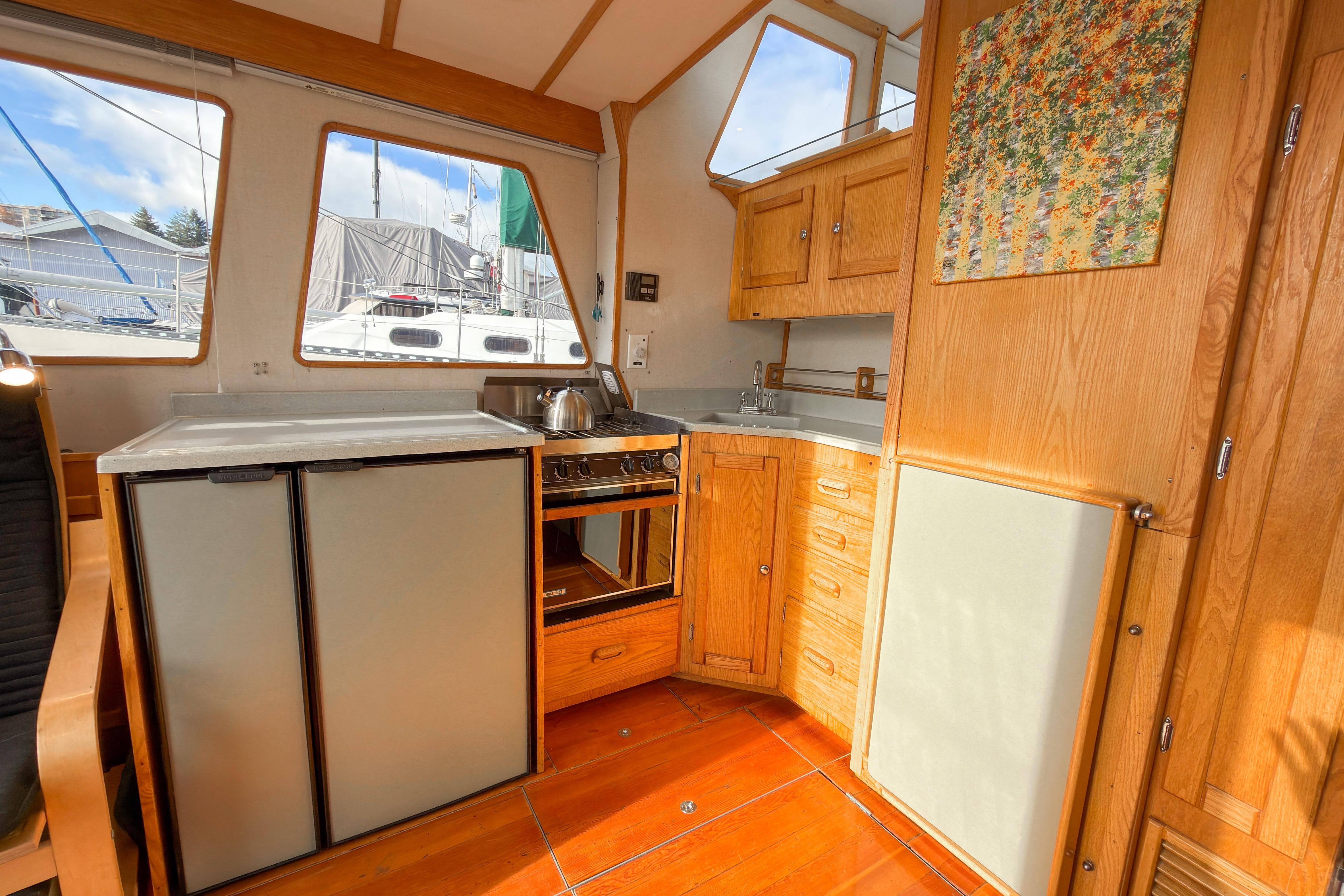 2014 Farrell 34 Pilothouse interior with kitchen, wooden cabinetry, and large windows.