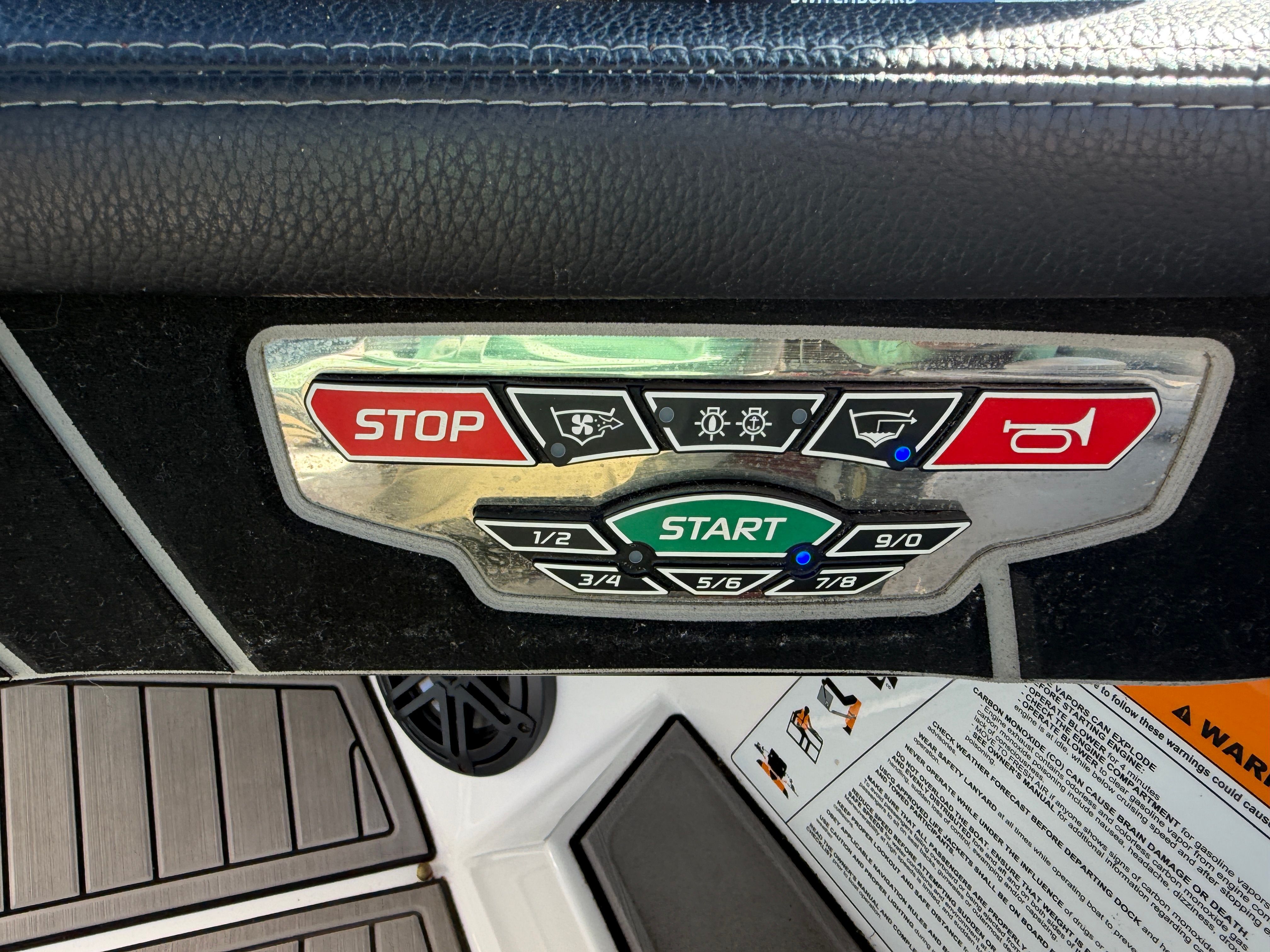 Close-up of a 2018 Nautique Super Air Nautique GS22 control panel with start and stop buttons.