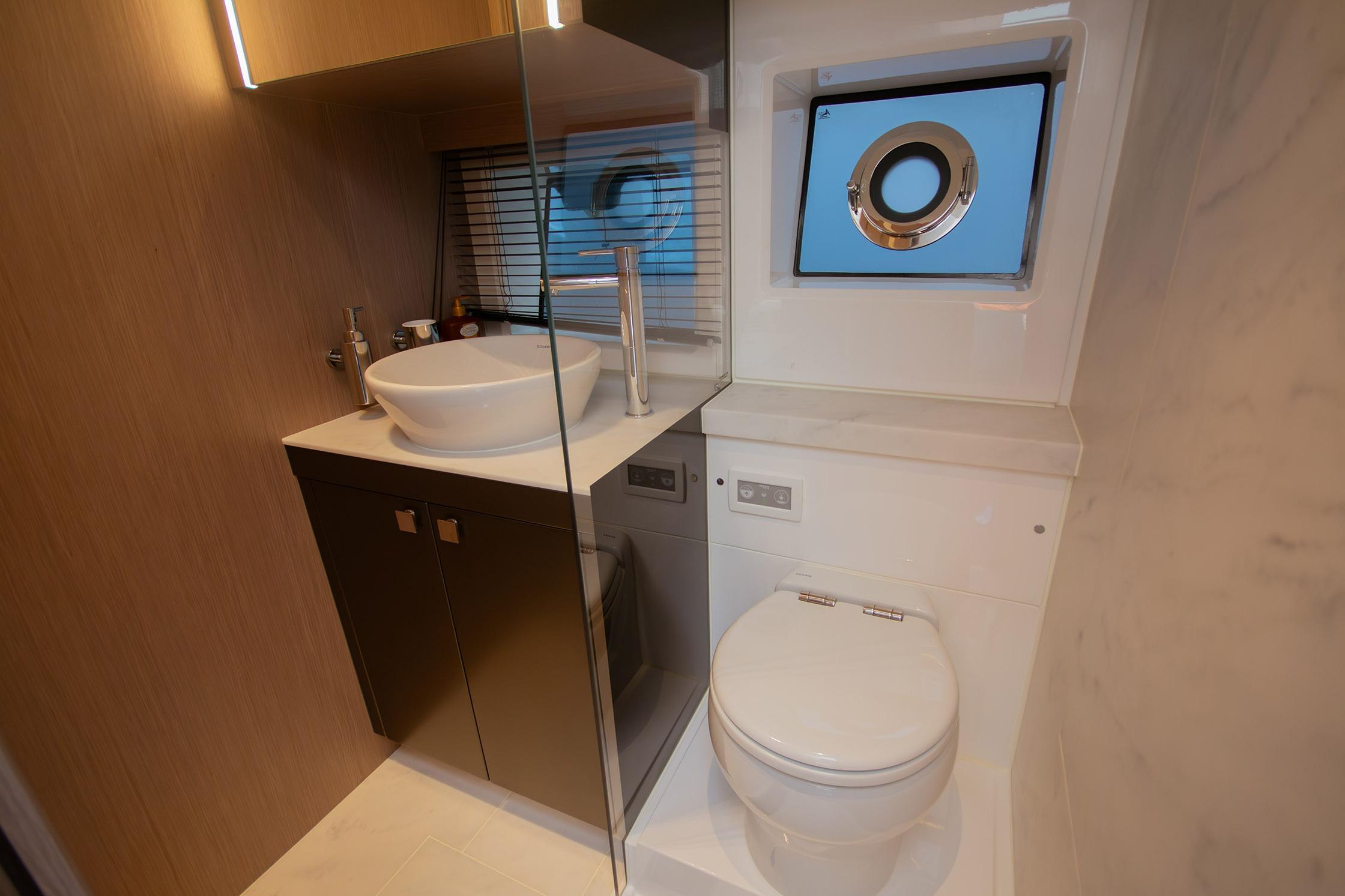 Luxurious bathroom in 2024 Sunseeker Superhawk 55 yacht with modern fixtures and porthole window.
