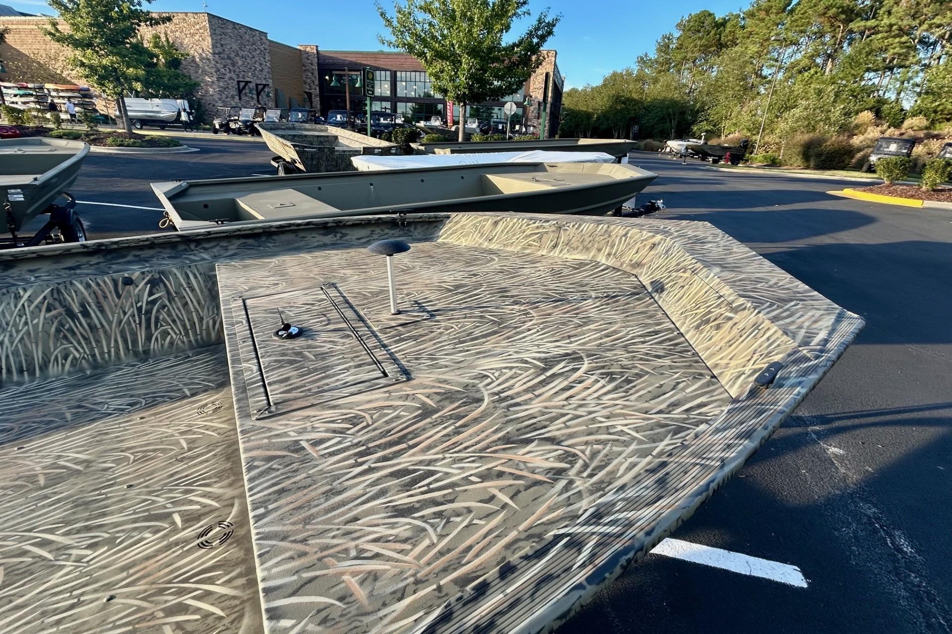 2026 Tracker Grizzly 1860 Utility boat with camouflage design in a parking lot.