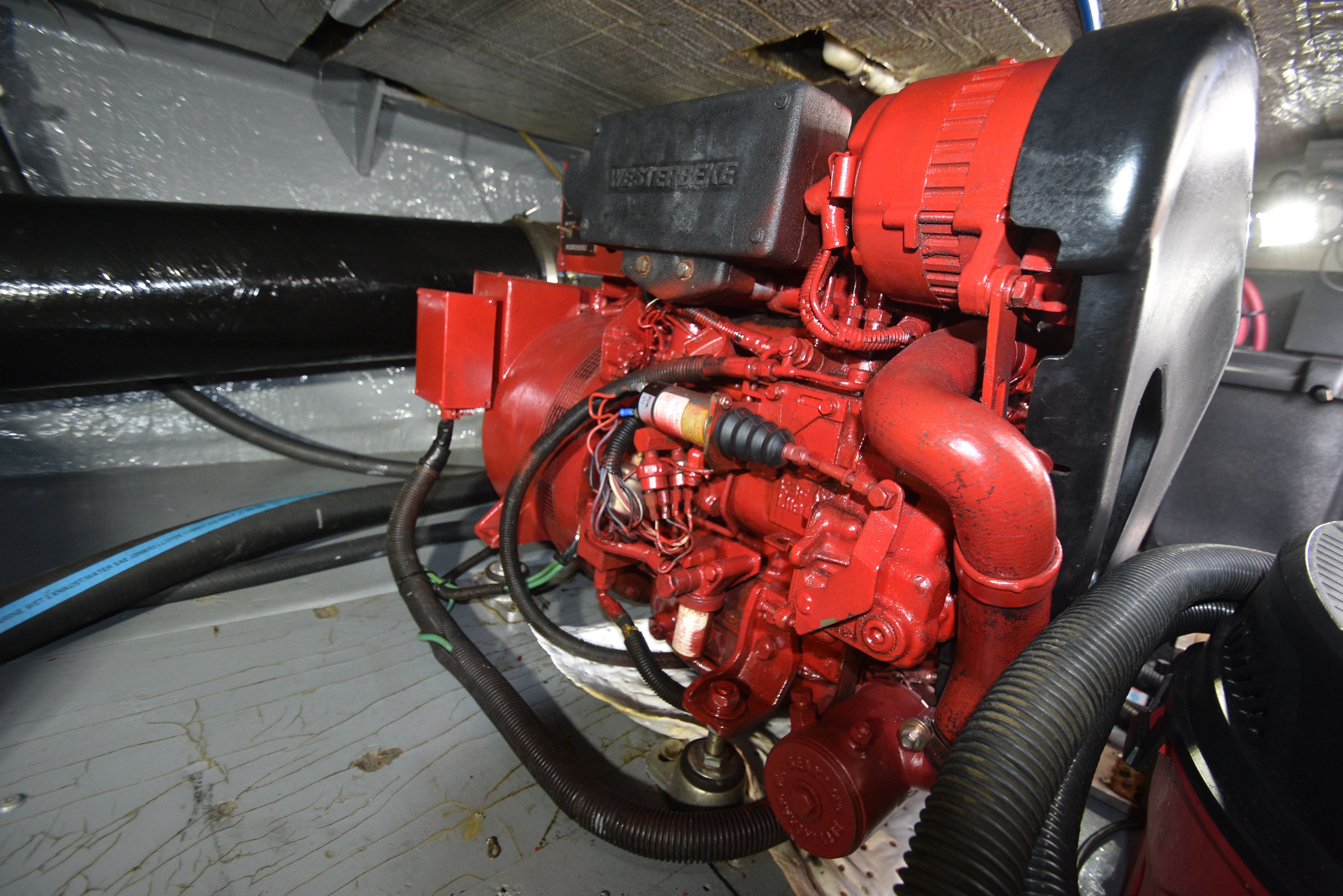 A red engine in a boat's engine room with various hoses and wires.
