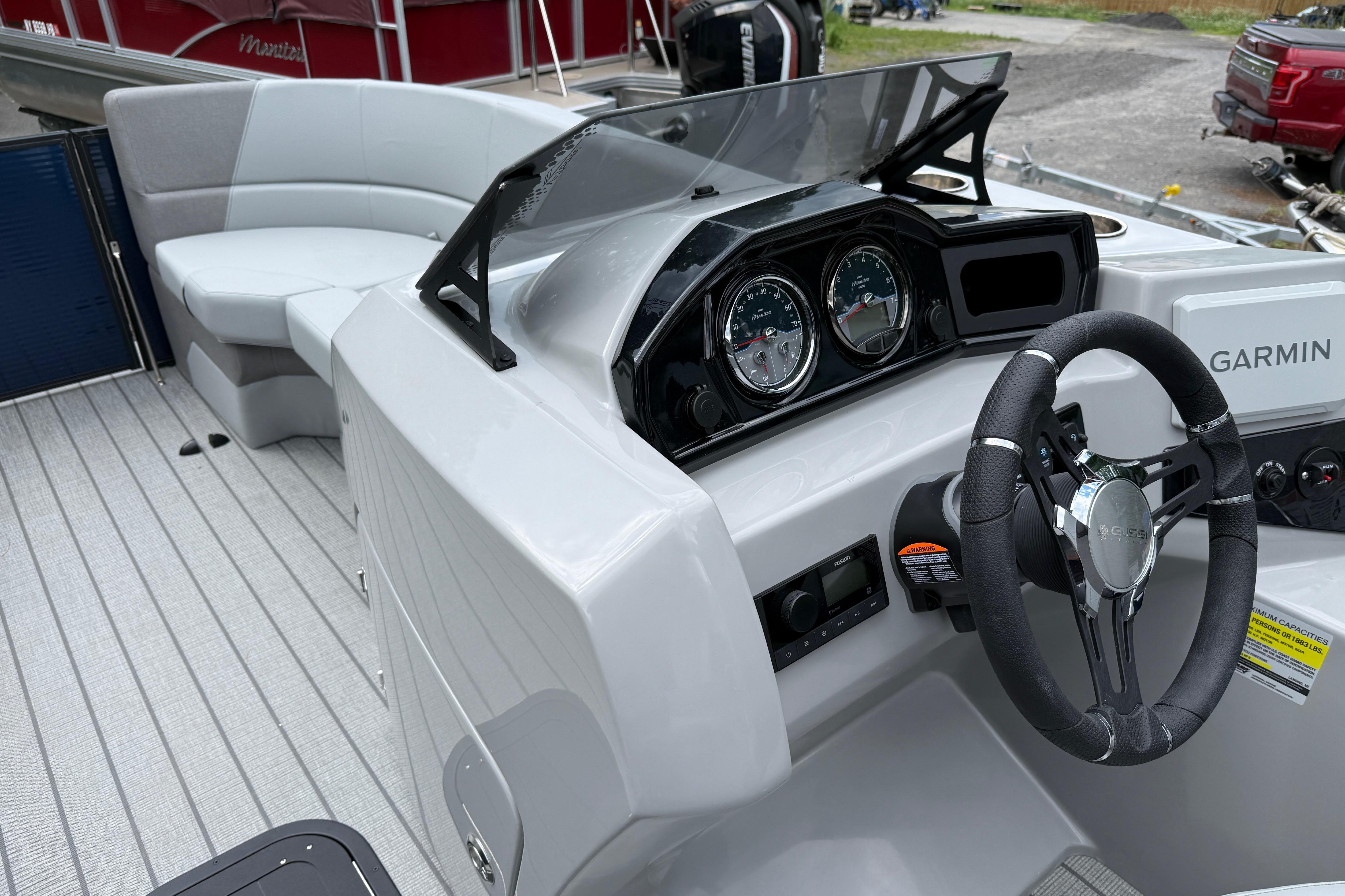 2027 Manitou Aurora RF 23 boat interior with steering wheel and Garmin navigation system.