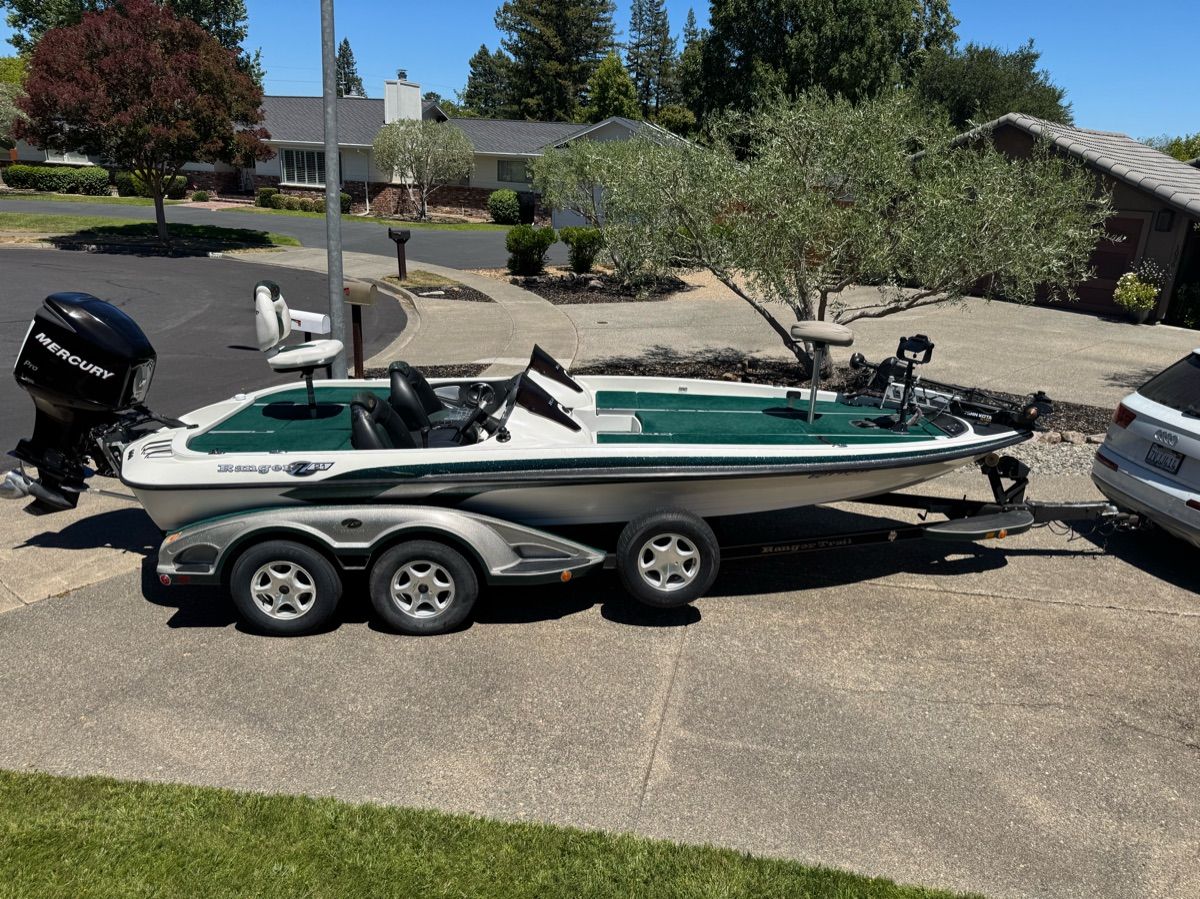A 2005 Ranger Z-21 boat on a trailer, parked in a residential area with trees in the background.
