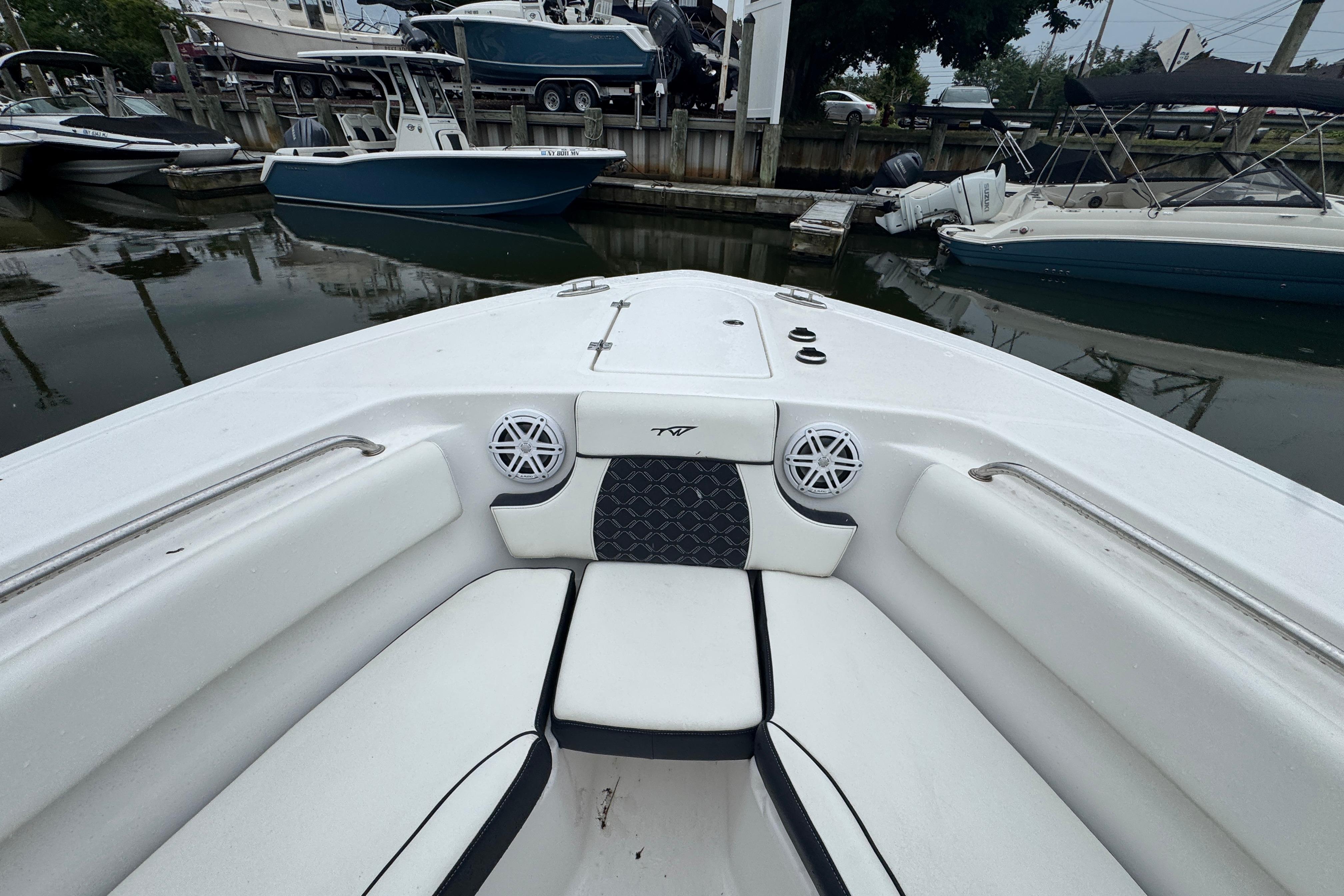 2022 Tidewater 232 SS boat interior with seating and speakers at a marina.