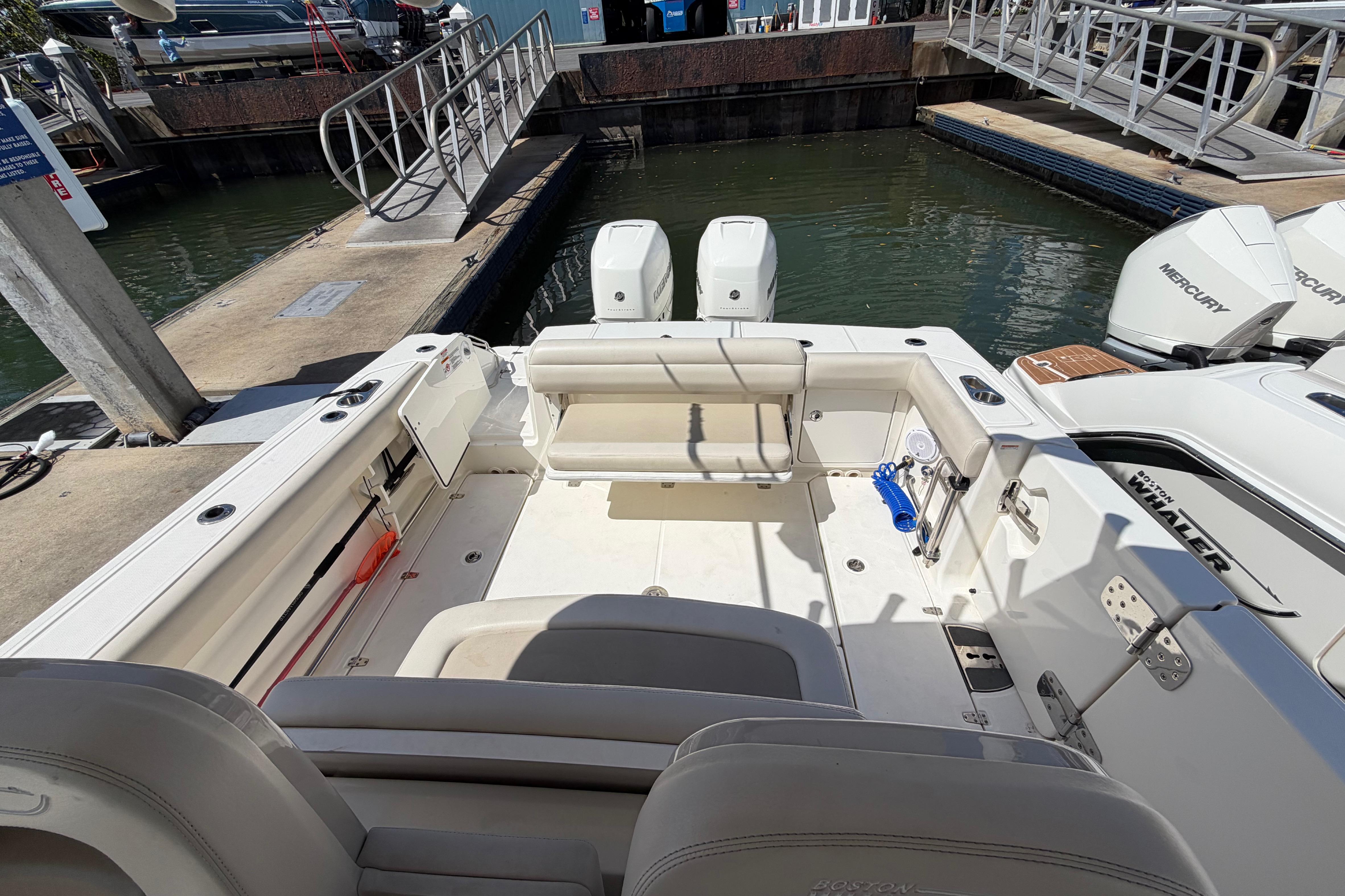2019 Boston Whaler 330 Outrage boat interior at dock, featuring seating and twin Mercury engines.