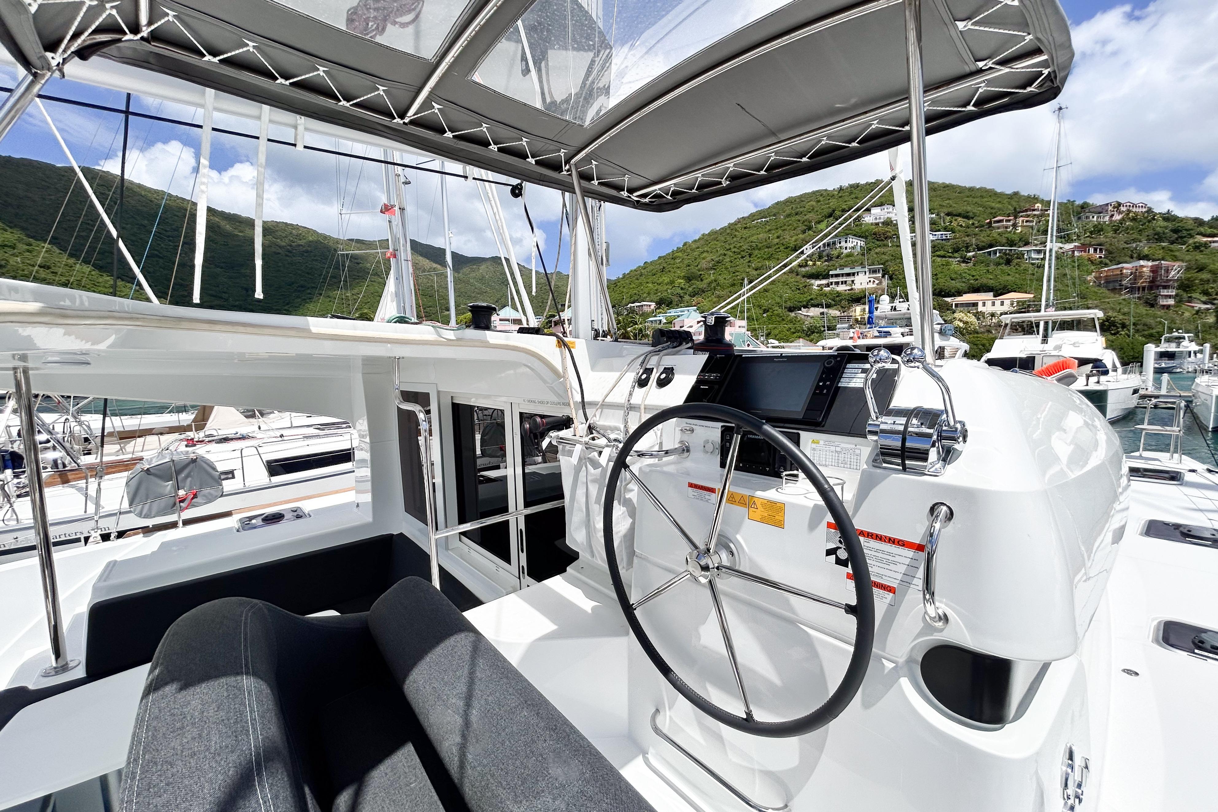 2025 Lagoon 40 yacht helm station with scenic marina backdrop.