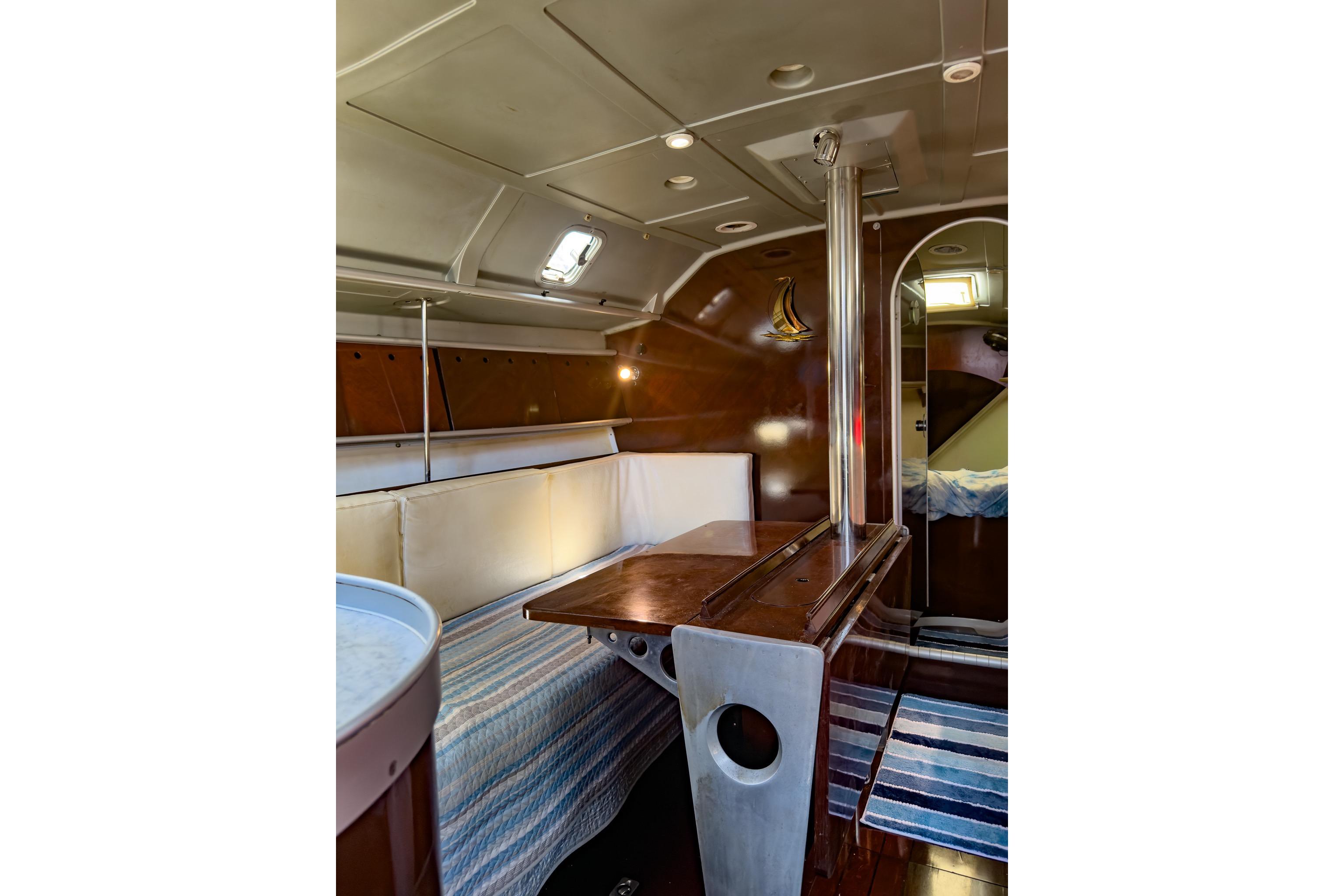 Interior of 1993 Beneteau First 38 s5 sailboat, featuring cozy seating and wooden table.