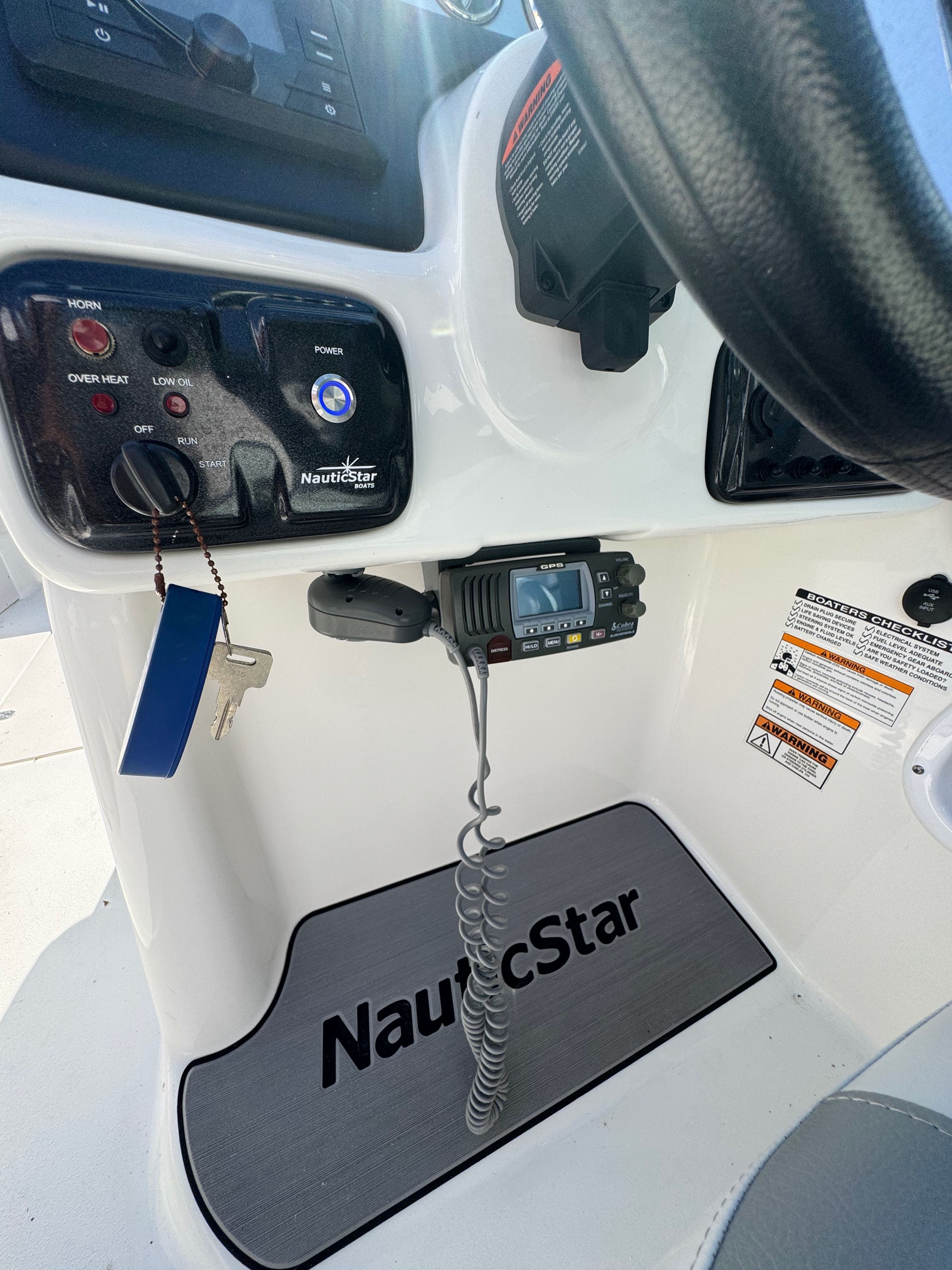 The image shows the helm of a 2022 NauticStar 243 DC boat with controls and a radio.