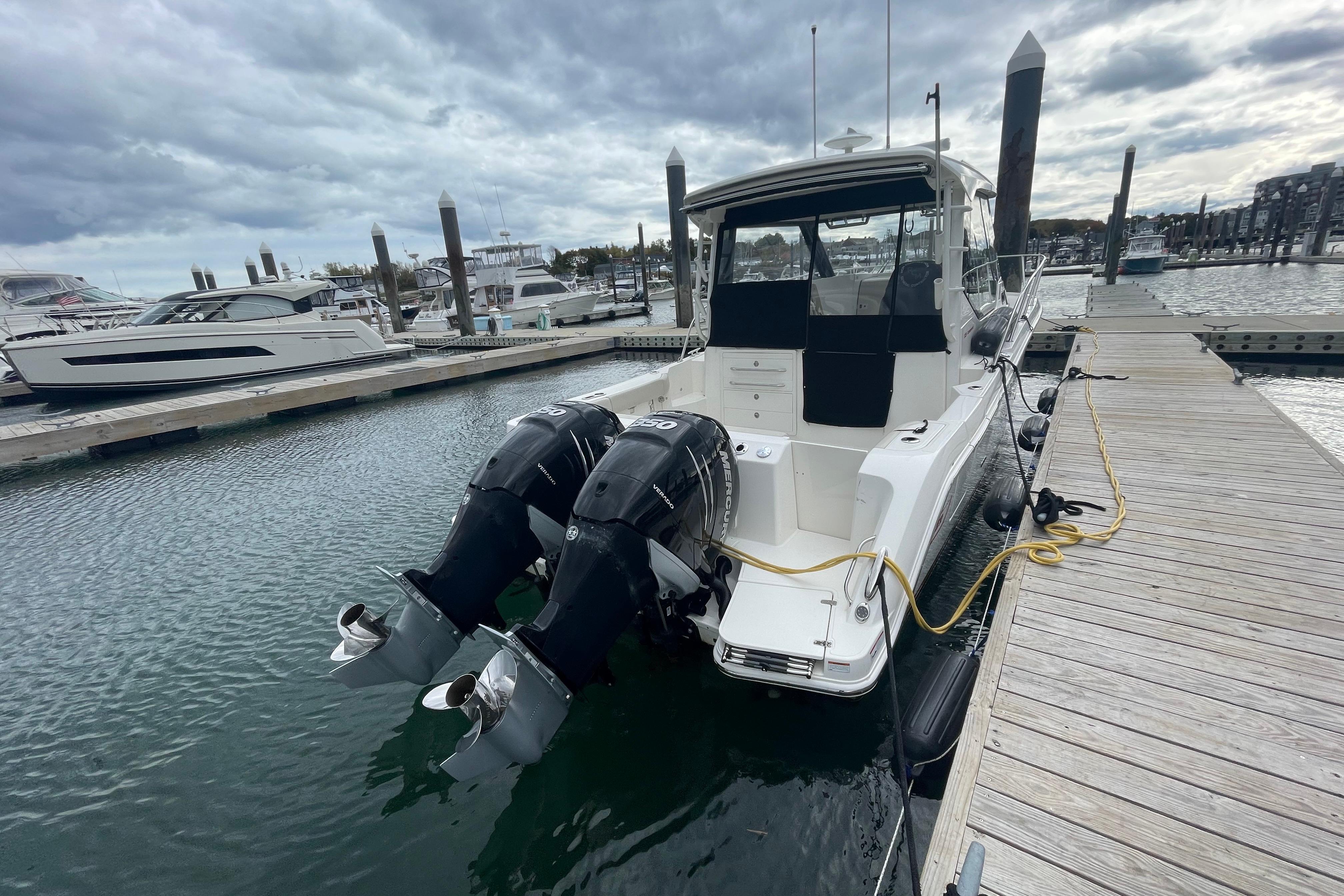 2023 Boston Whaler 325 Conquest docked, featuring dual outboard engines, under cloudy skies.
