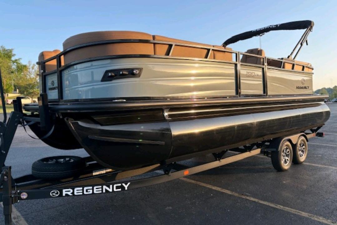 2026 Regency 230 DL pontoon boat on trailer, parked outdoors in sunlight.