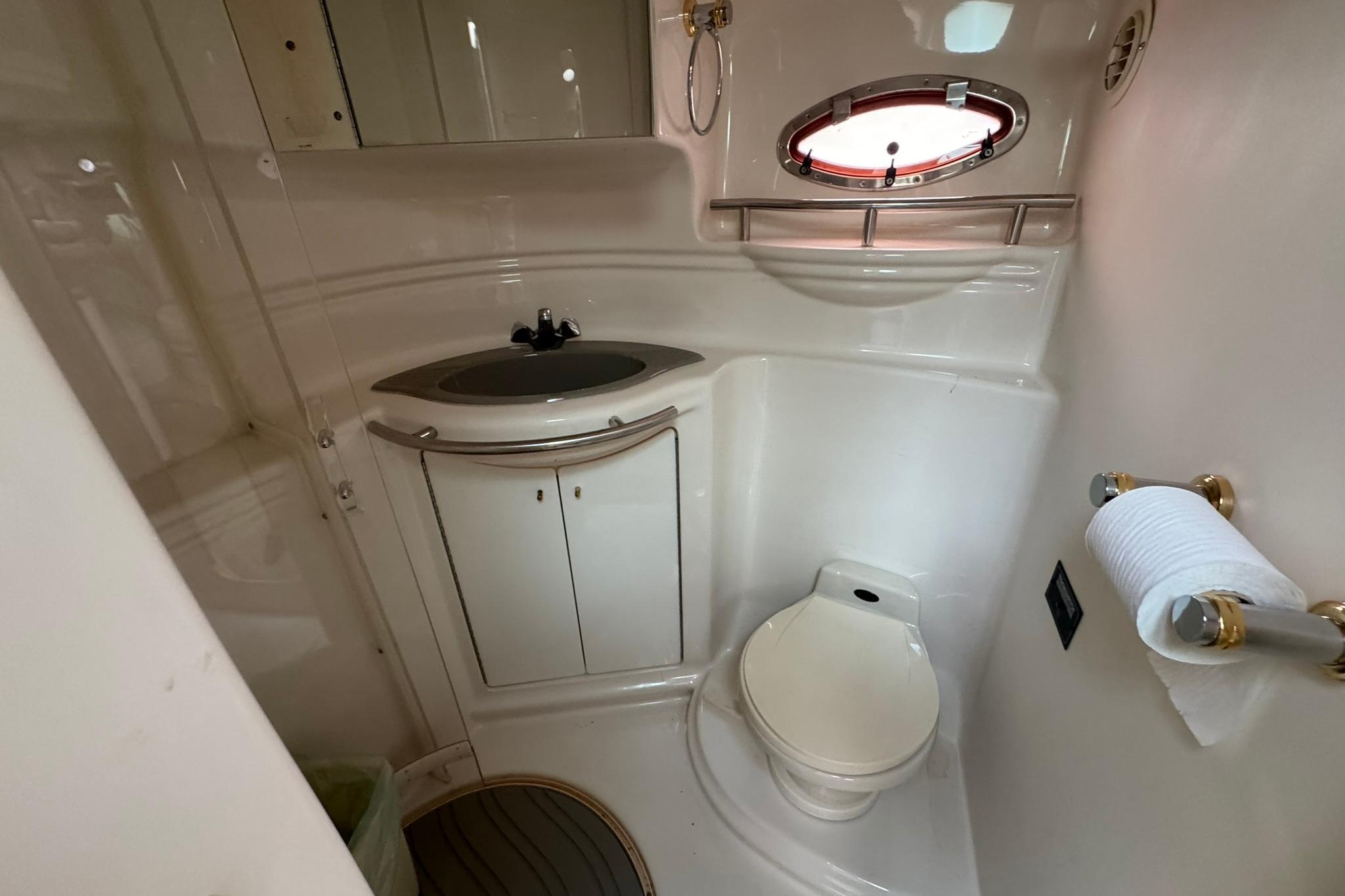 1998 Maxum 3700 SCR yacht bathroom with sink, toilet, and porthole window.