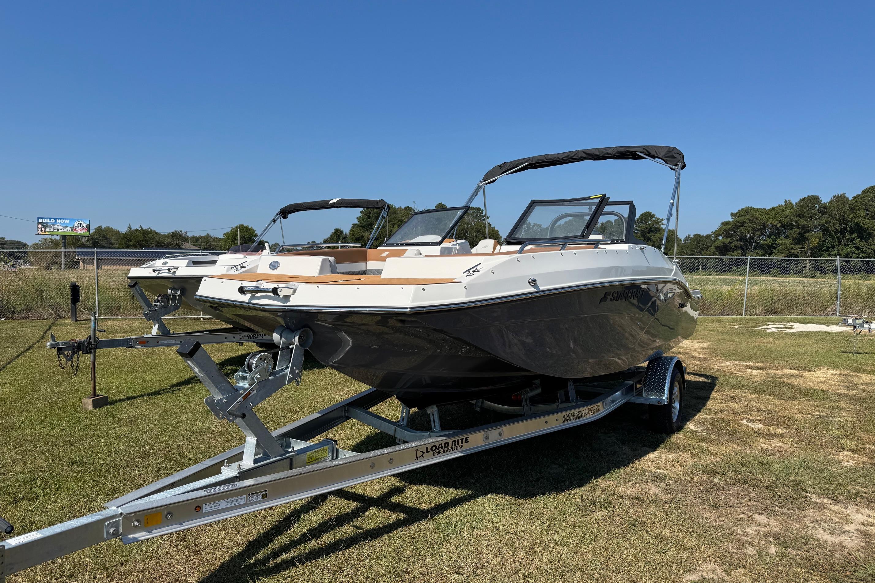 2026 Starcraft SVX 190 OB boat on trailer, parked on grass under clear blue sky.