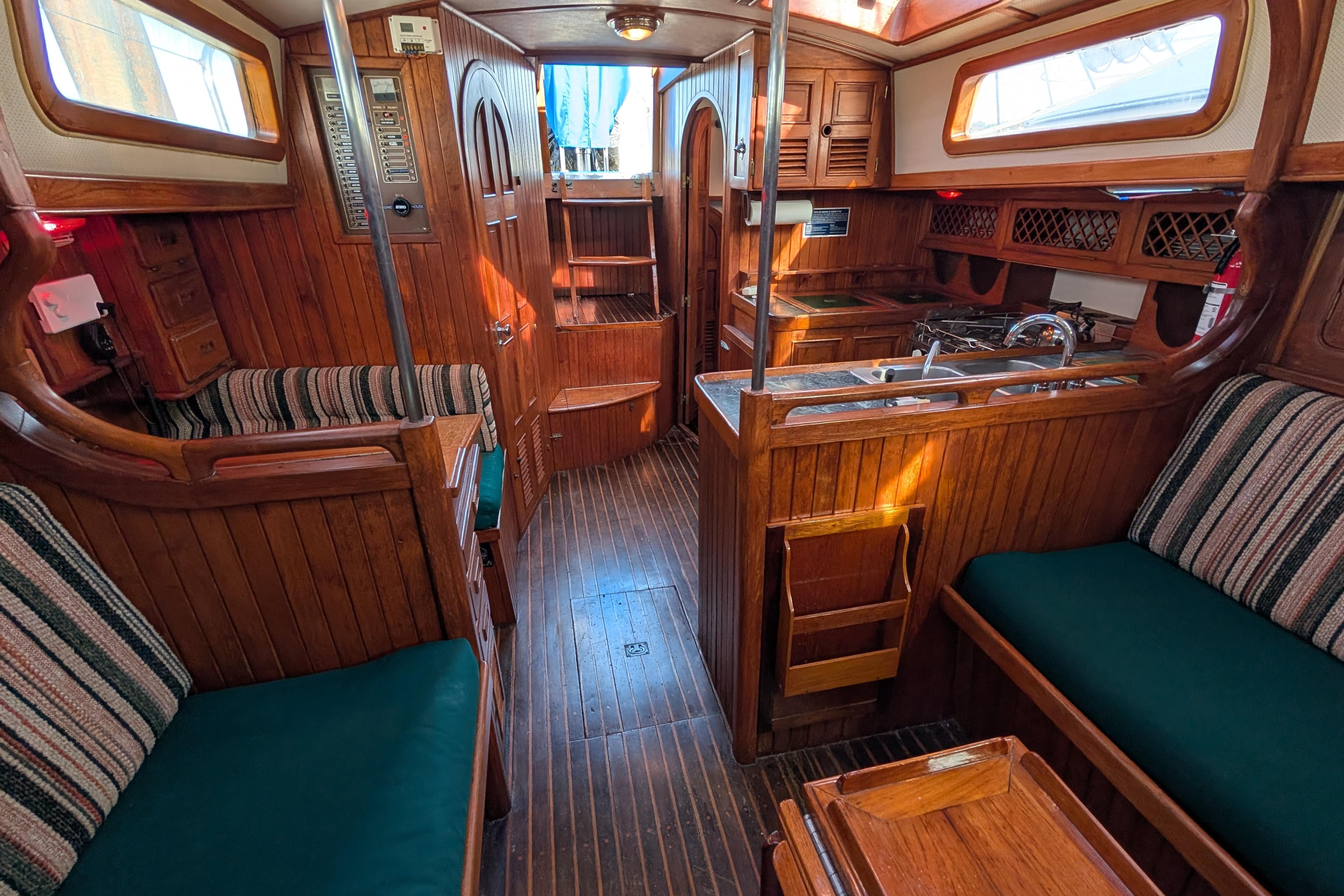 Interior of a 1983 Robert Perry 41 sailboat with wooden furnishings and cozy seating.