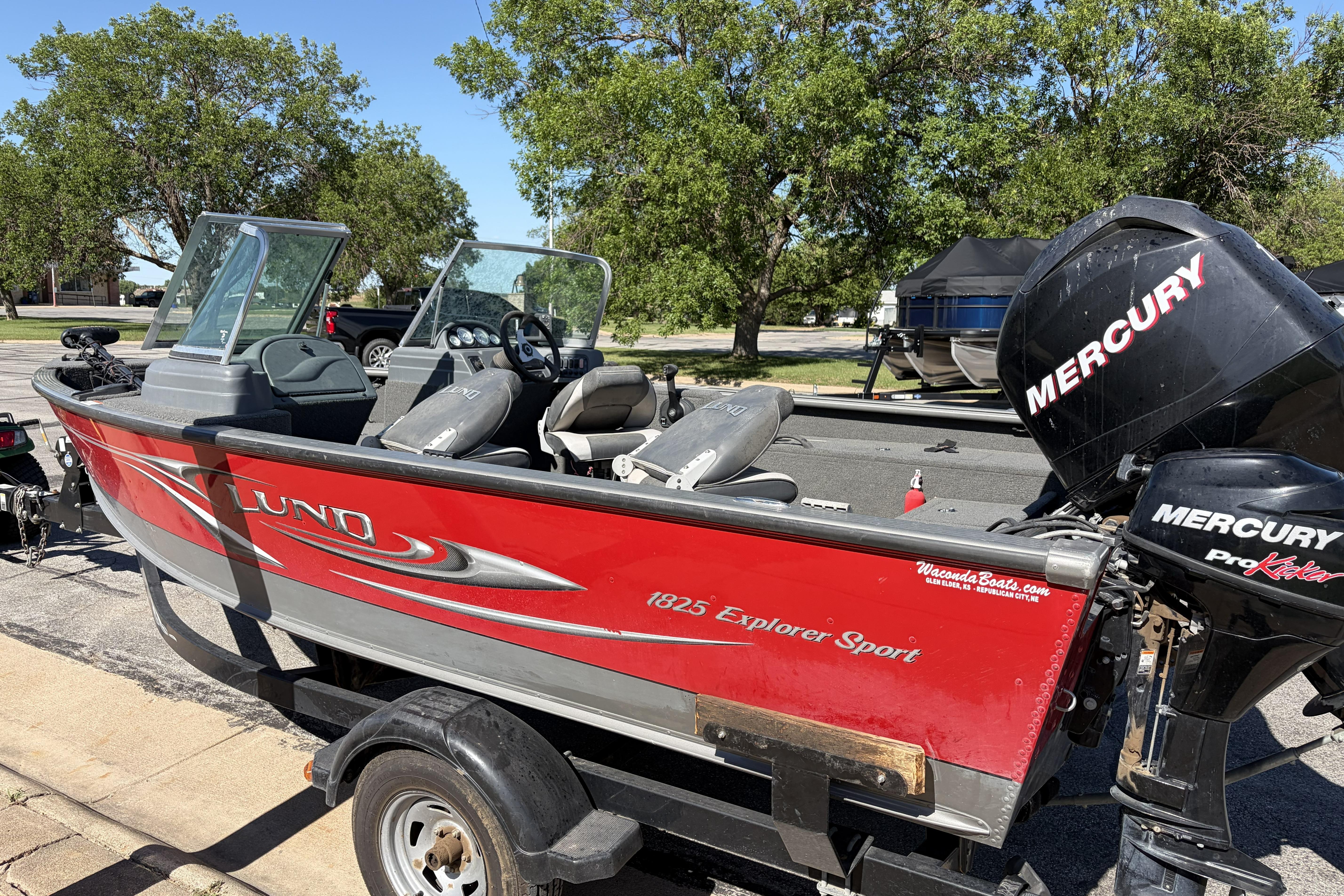 2010 Lund 1825 Explorer boat with Mercury engine on trailer, parked outdoors.