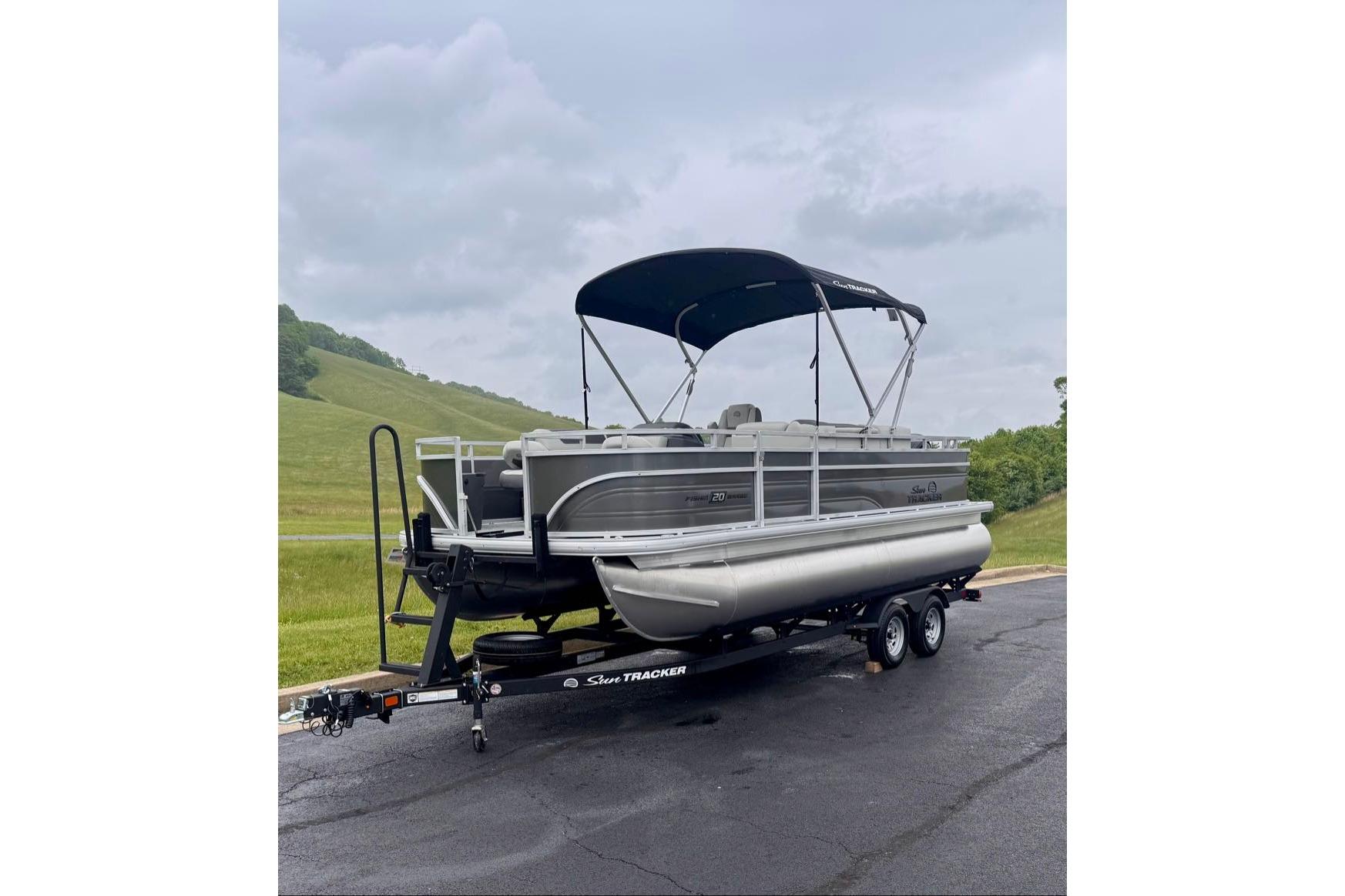 2026 Sun Tracker Fishin' Barge 20 DLX pontoon boat on trailer, parked outdoors.