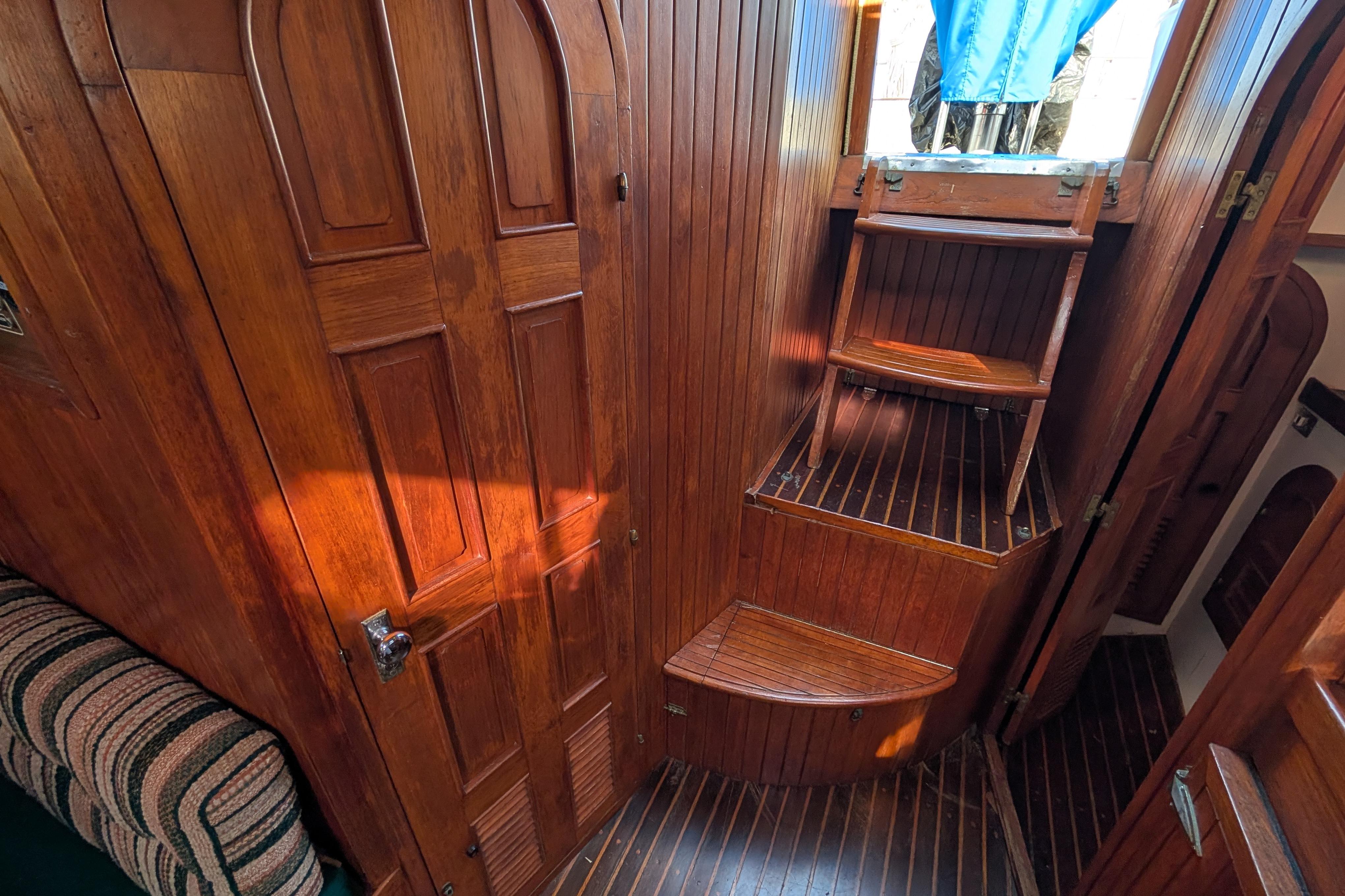 Interior of 1983 Robert Perry 41 sailboat with wooden paneling and steps.