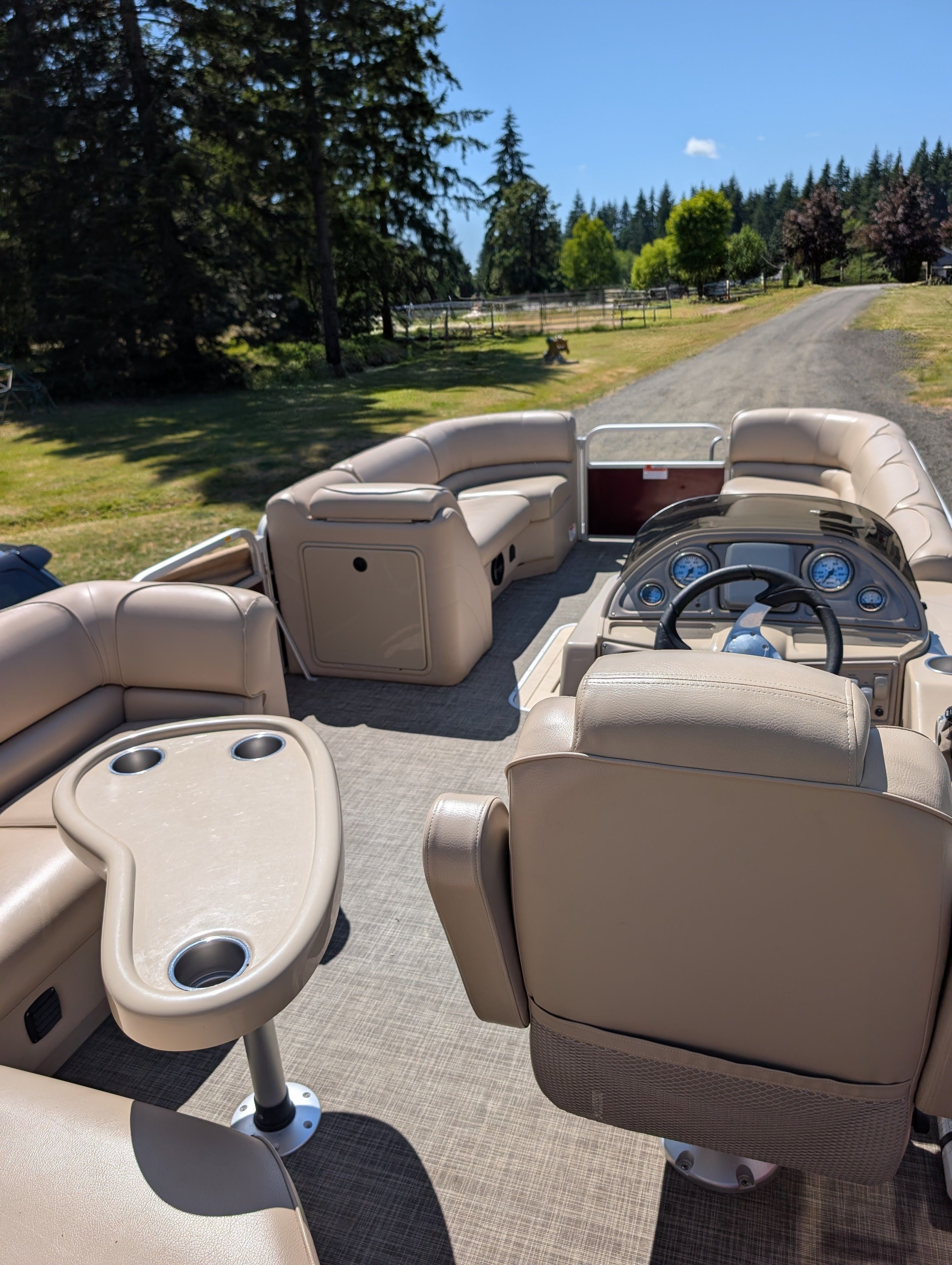 Interior view of a 2016 SunCatcher V322 GX pontoon boat with beige seating and a helm station.