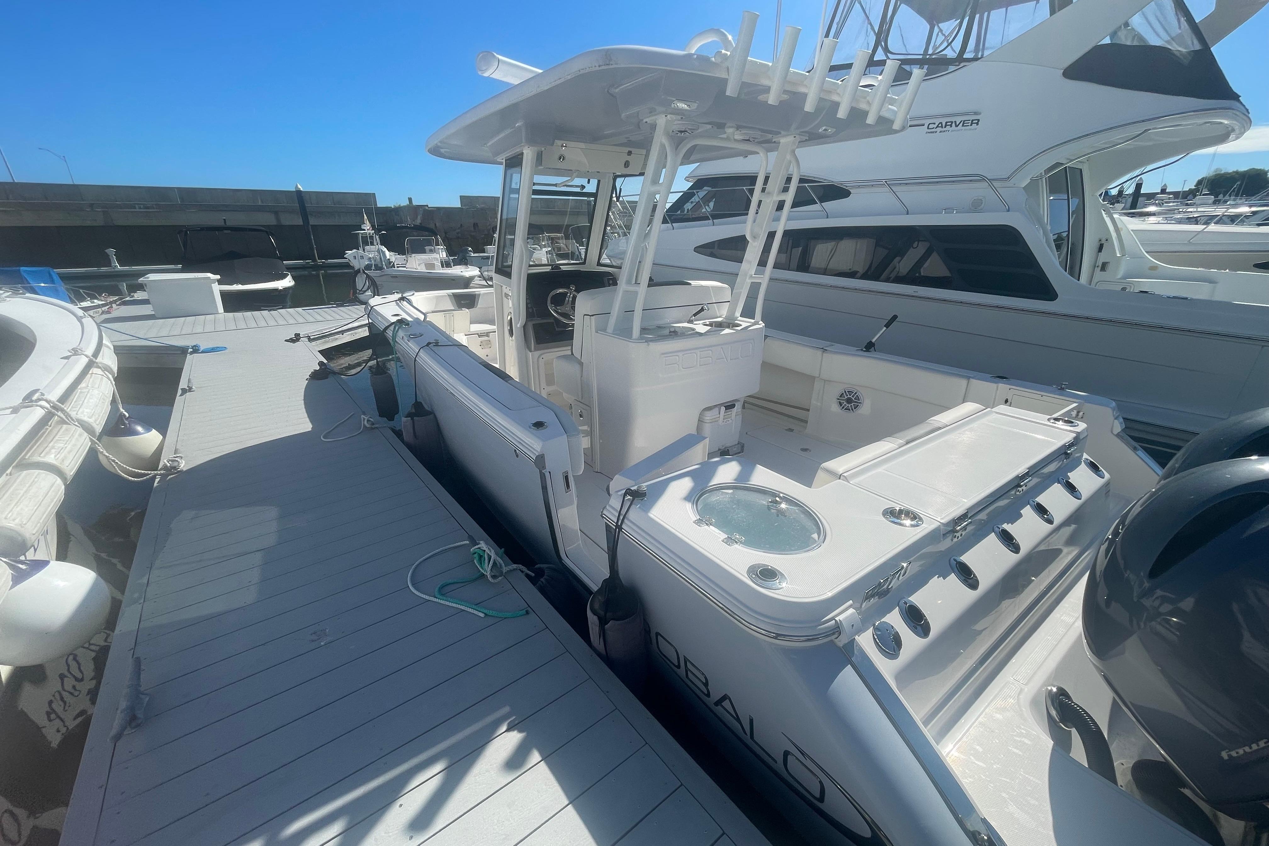 2023 Robalo R270 Center Console boat docked at marina under clear blue sky.