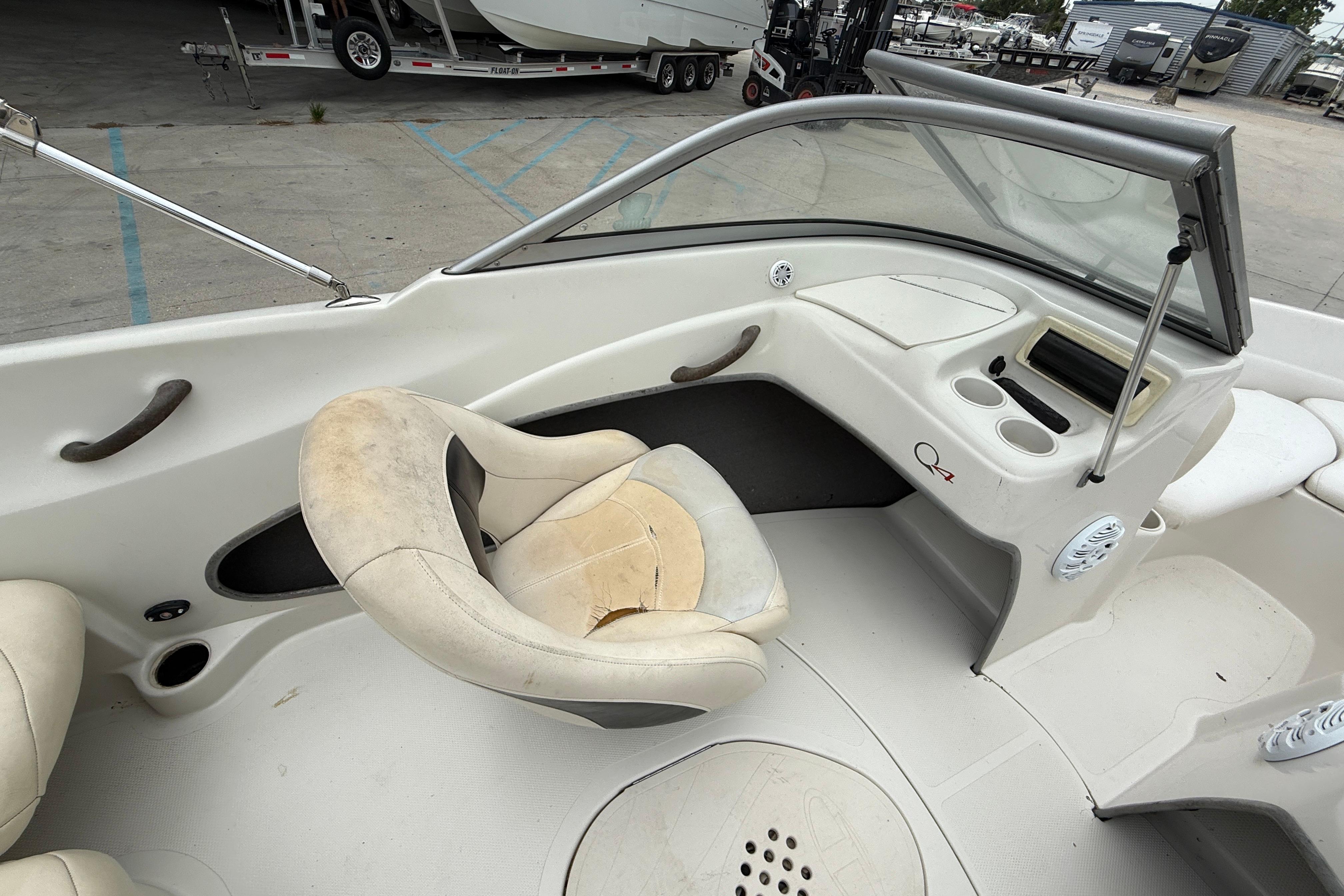 2010 Tahoe Q4 boat interior with worn seating and dashboard, parked in a marina.