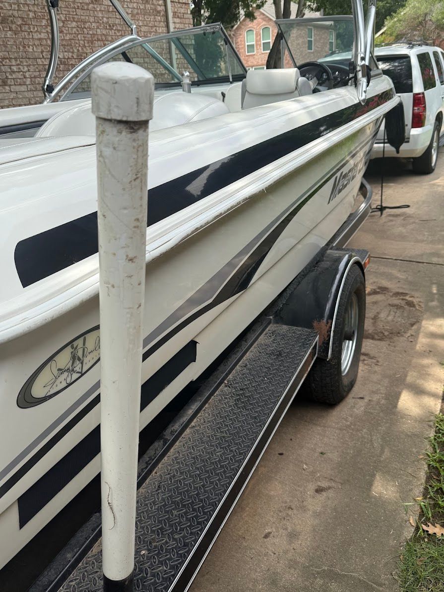 A 1999 MasterCraft Prostar 205 on a trailer in a driveway.