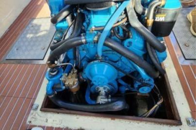 1985 Wasque Down East Cruiser engine, blue with black hoses, on a wooden deck.