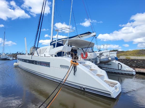 2009 Catana 65 catamaran docked in a marina under a clear blue sky.