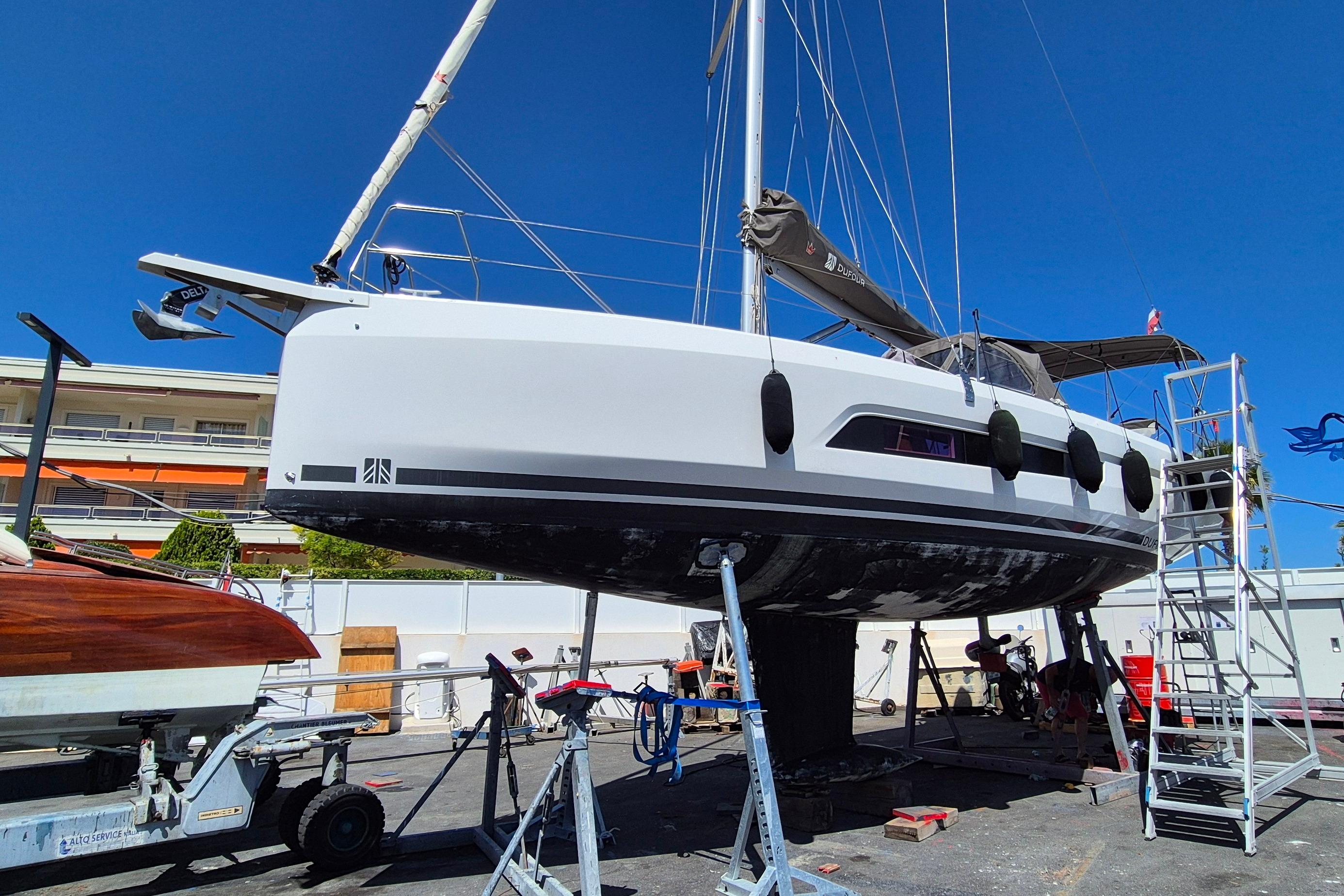 2023 Dufour 37 sailboat on dry dock, undergoing maintenance under clear blue sky.