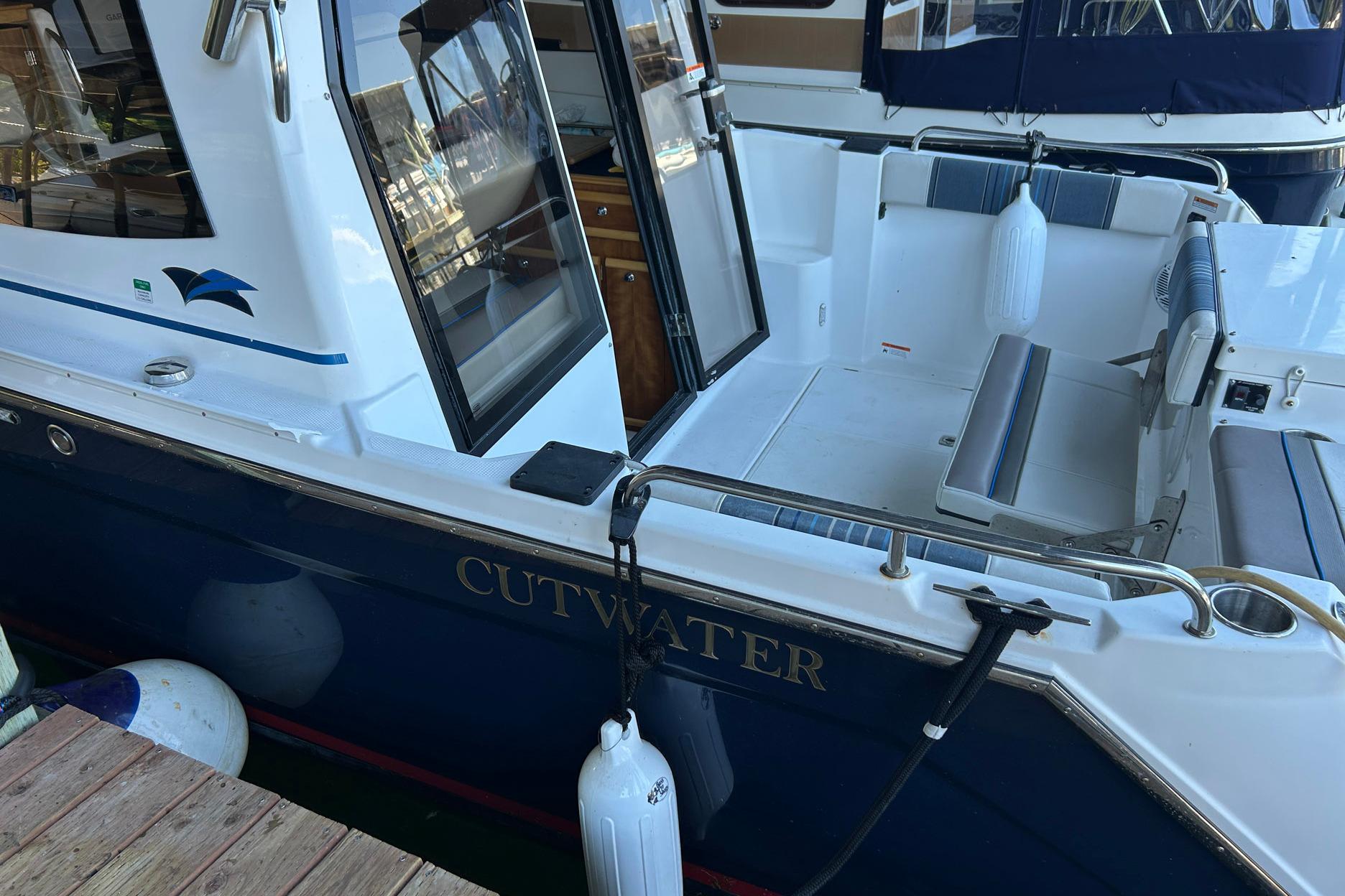 2017 Cutwater C-24 boat docked, featuring open seating area and sleek design.