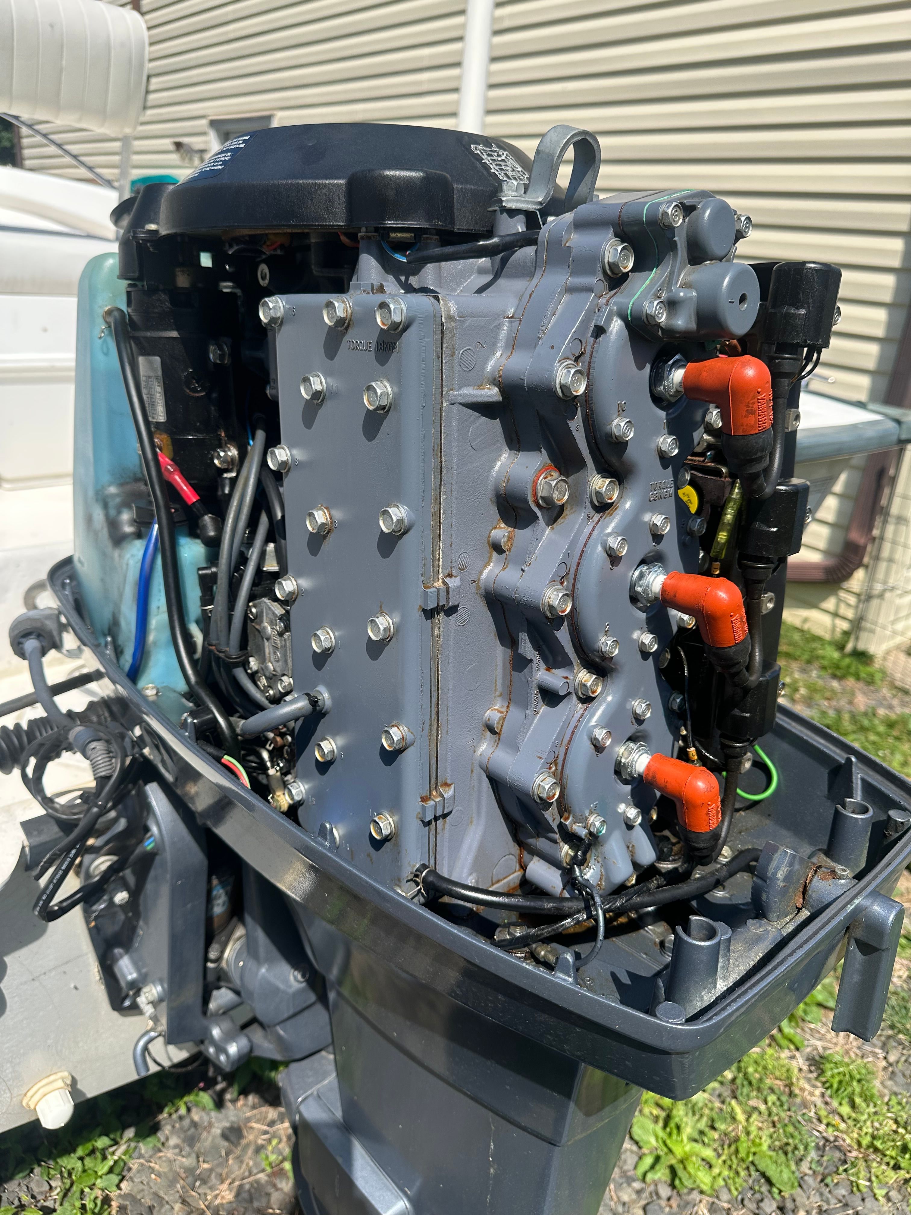 An outboard motor with exposed components, mounted on a boat, in front of a building.