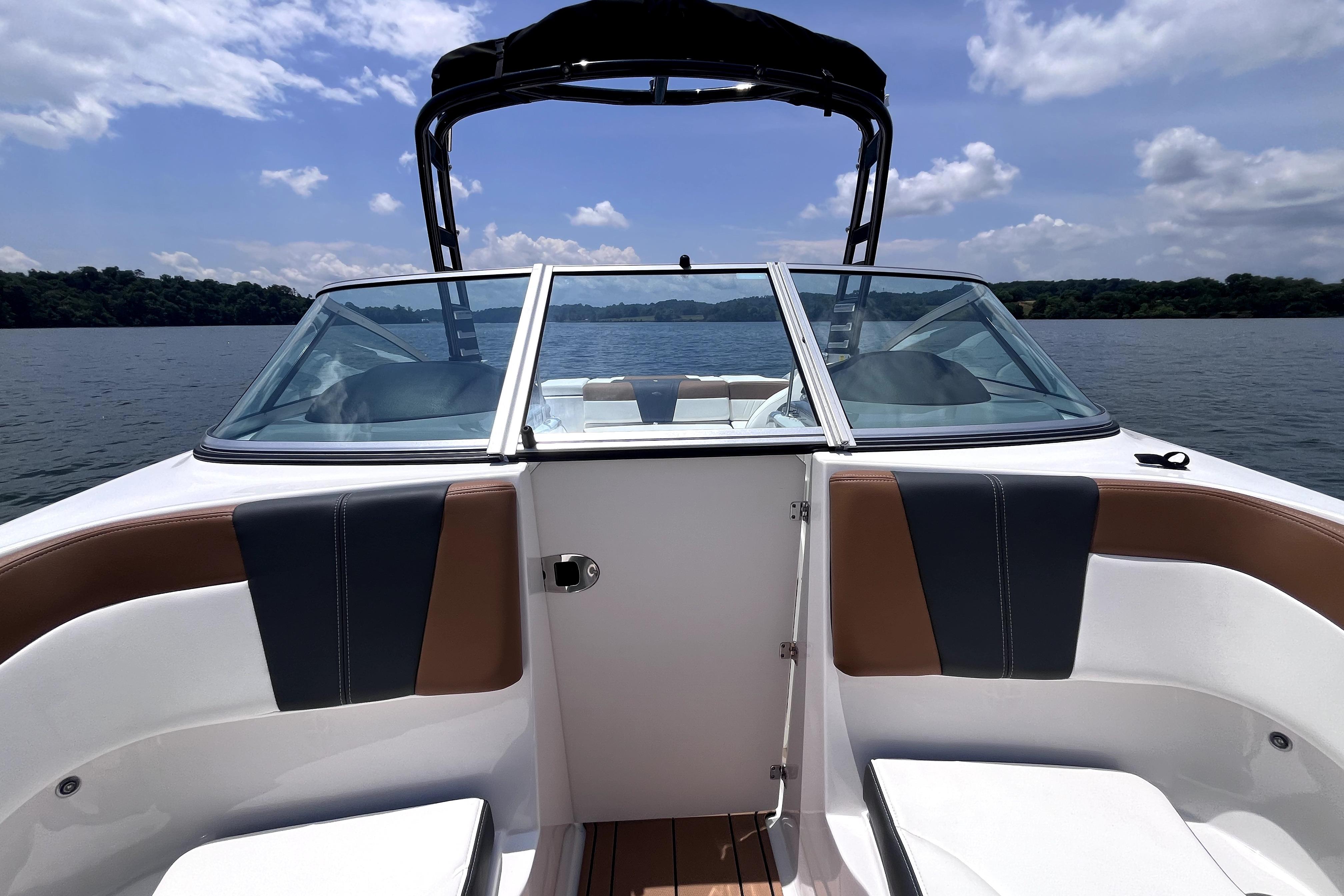 2025 Chaparral 230 SSi boat interior with seating, on a lake under a blue sky.