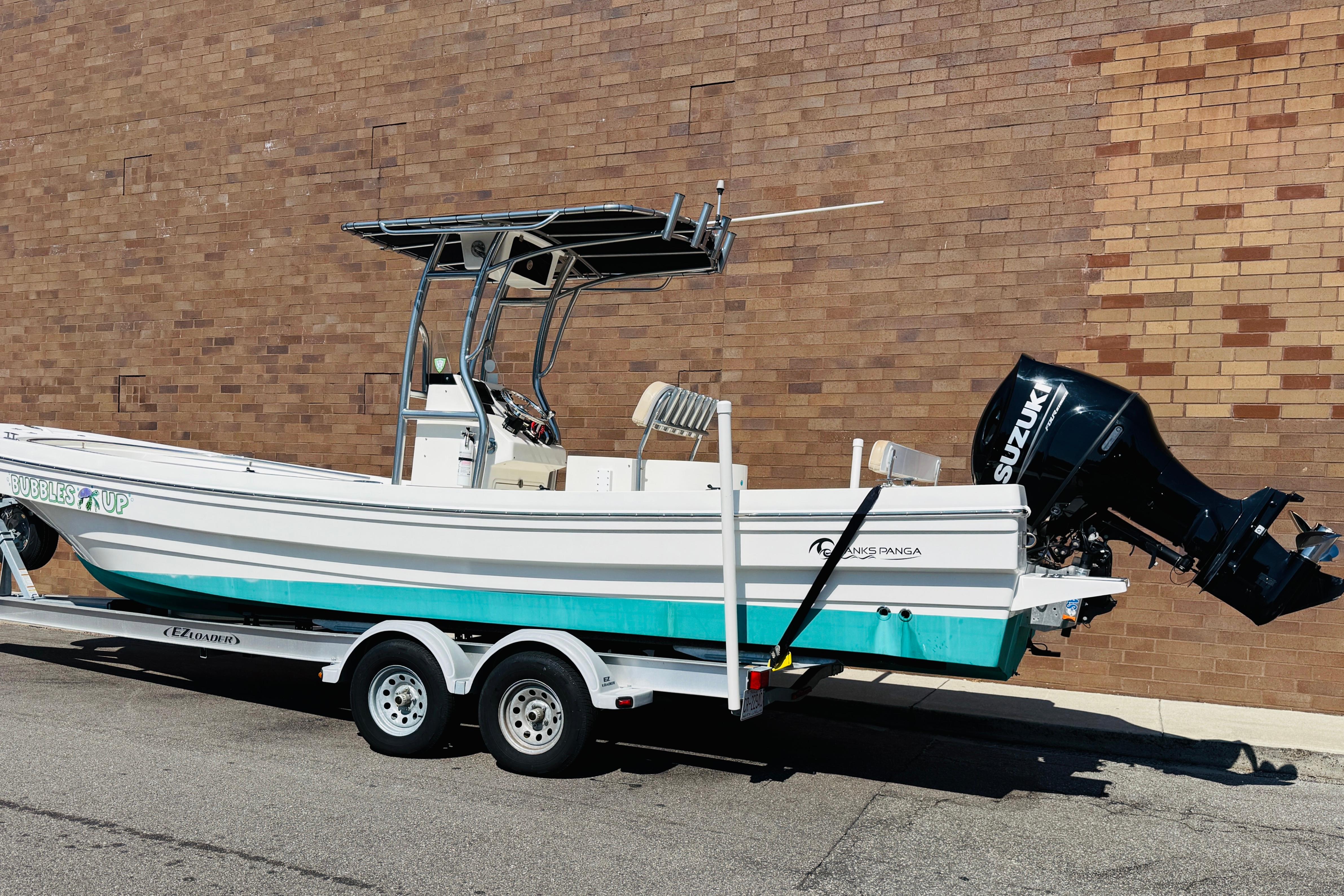 2023 Banks Panga 26 Center Console boat on trailer, parked by brick wall.