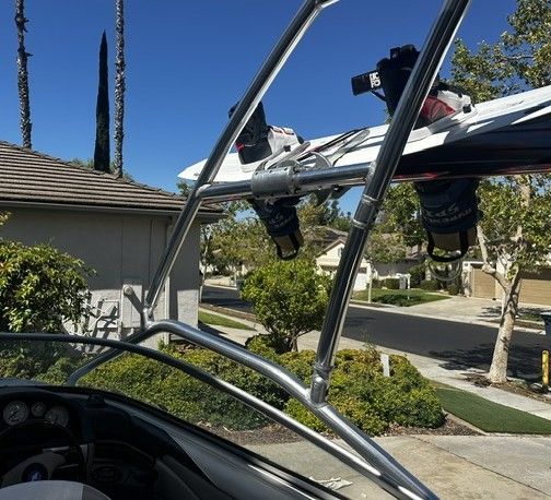 A boat with a wakeboard tower parked in a residential area.