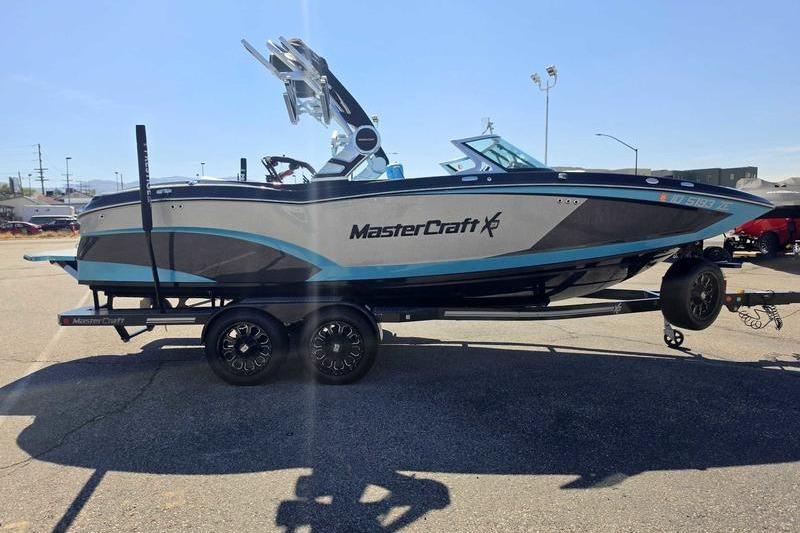 2017 MasterCraft X23 boat on trailer, parked outdoors under clear sky.