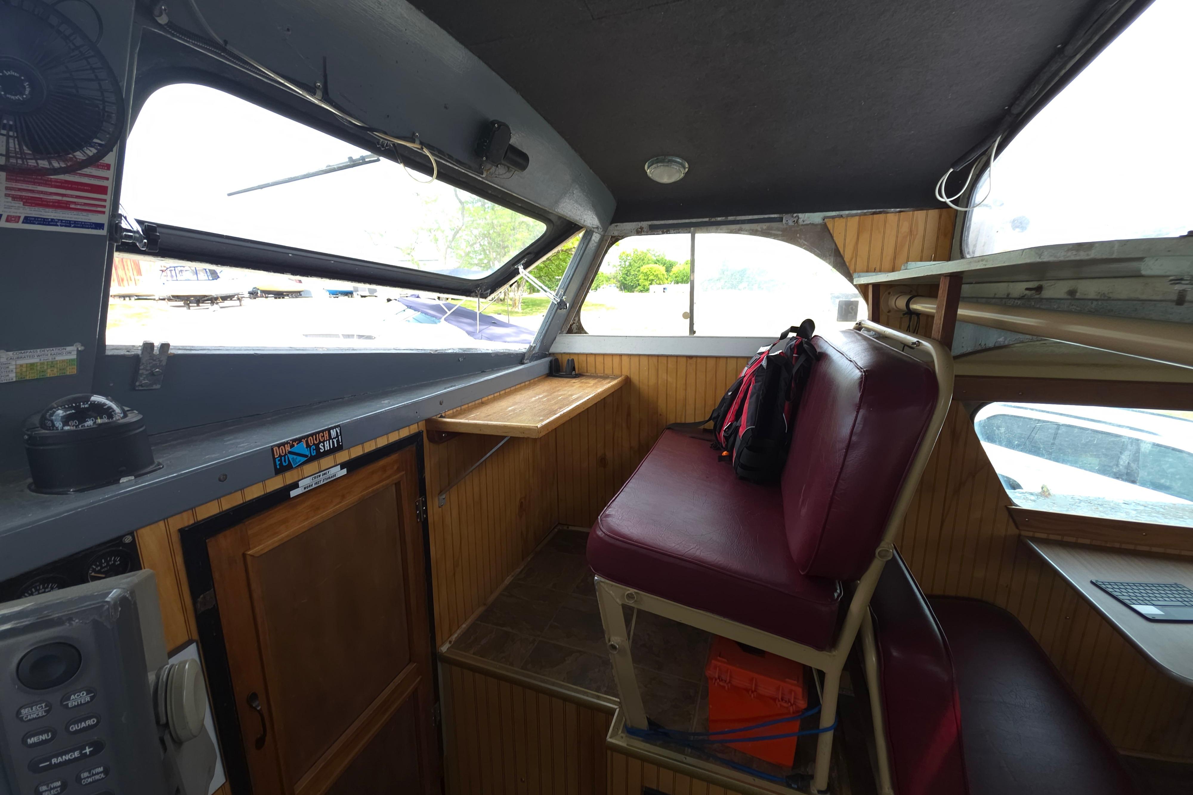 Interior of a 1974 Breaux's Bay Craft passenger boat with seating and wooden paneling.