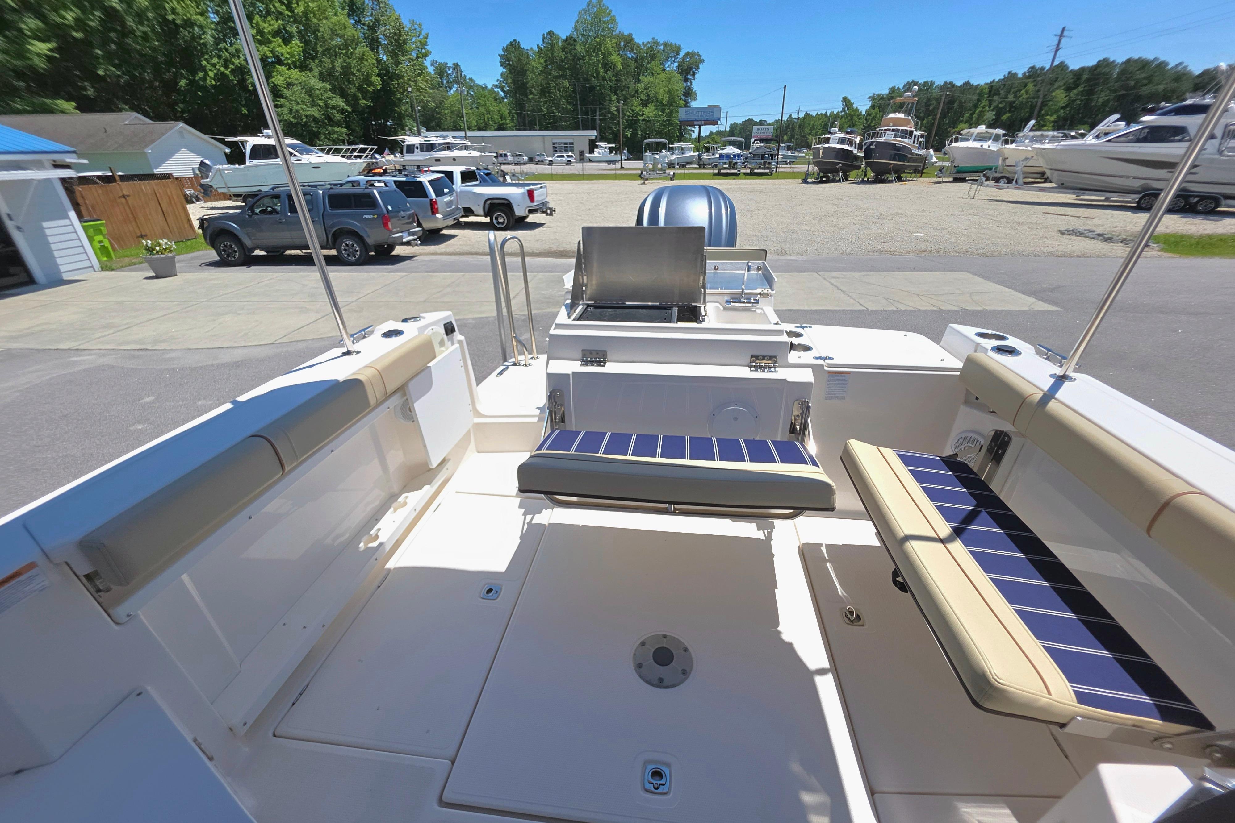 2021 Ranger Tug R27 boat deck with seating and outdoor grill in a marina setting.