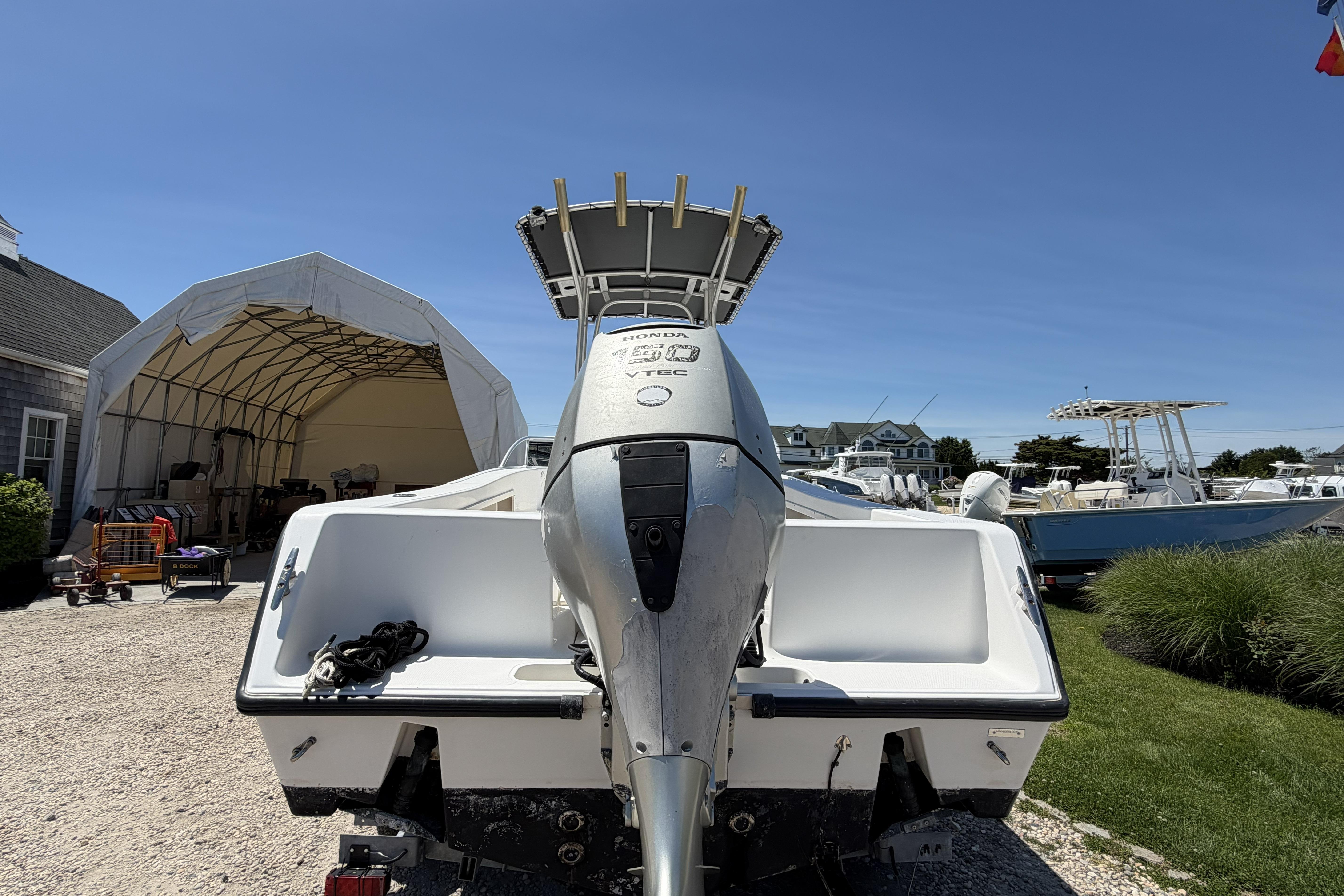 2006 Mako 212 Center Console boat with outboard motor, parked outdoors under clear blue sky.