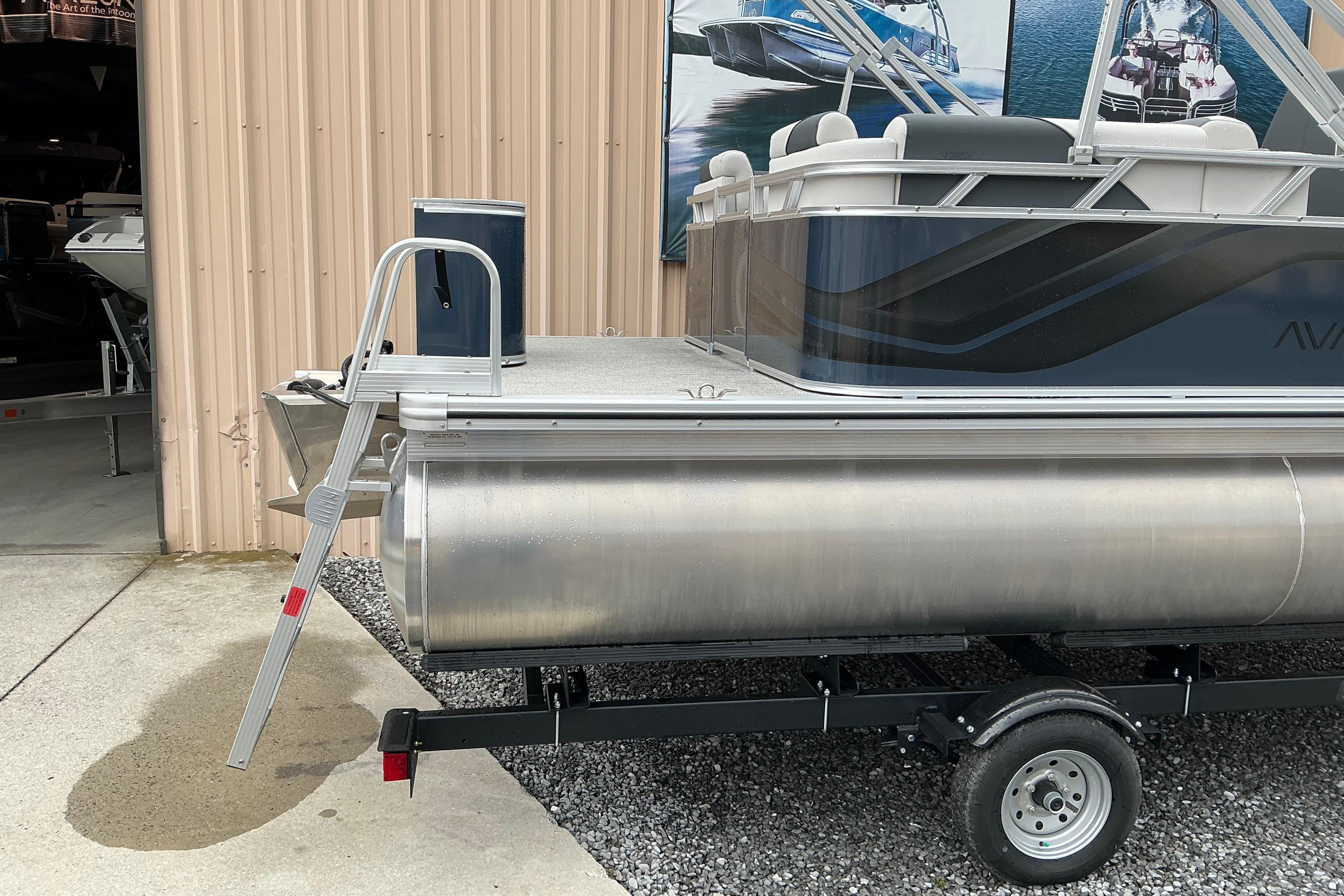 2026 Avalon Venture Quad Lounge 21' pontoon boat on trailer near a building.