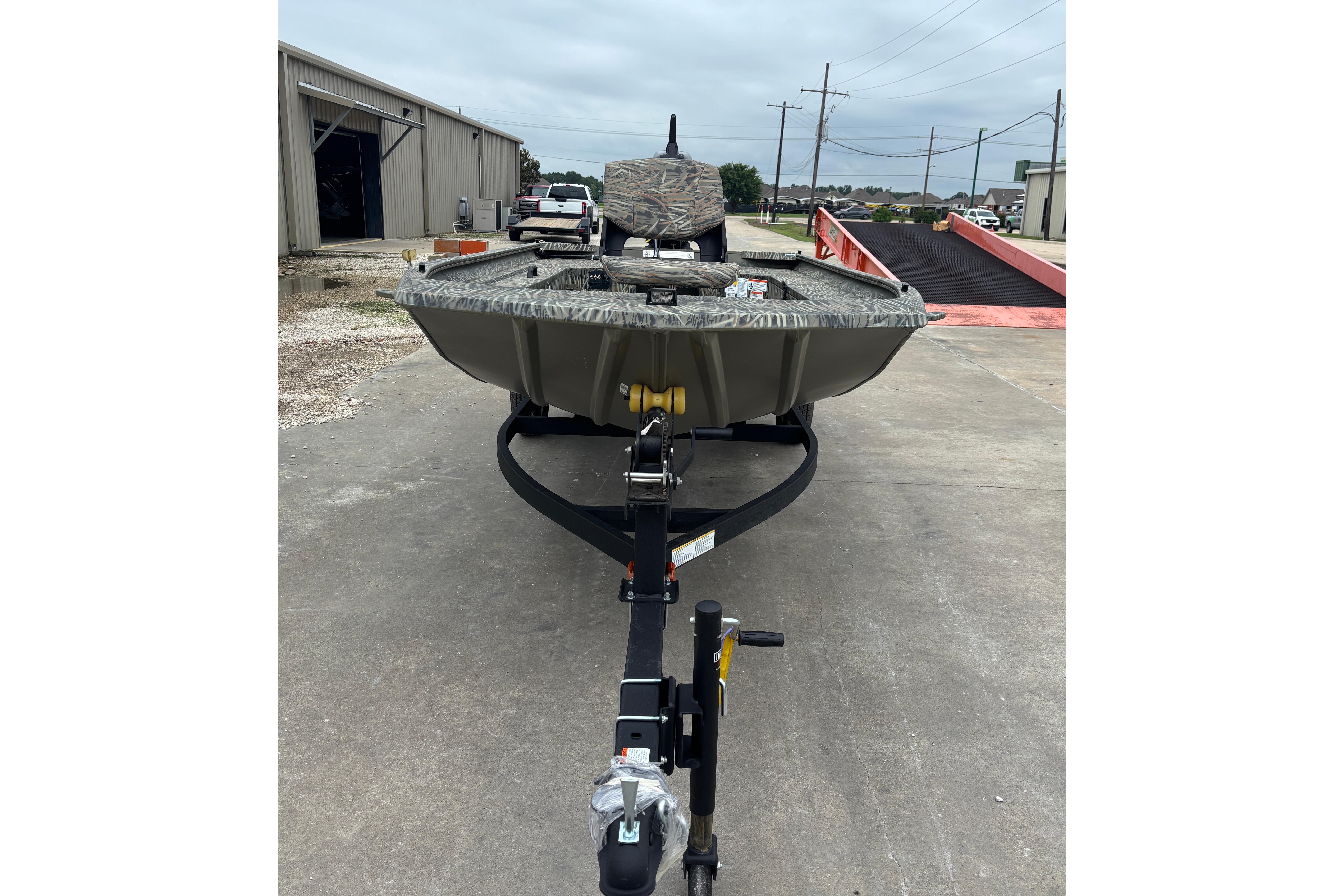 2026 Tracker Grizzly 1654 T Sportsman boat on trailer in industrial setting.