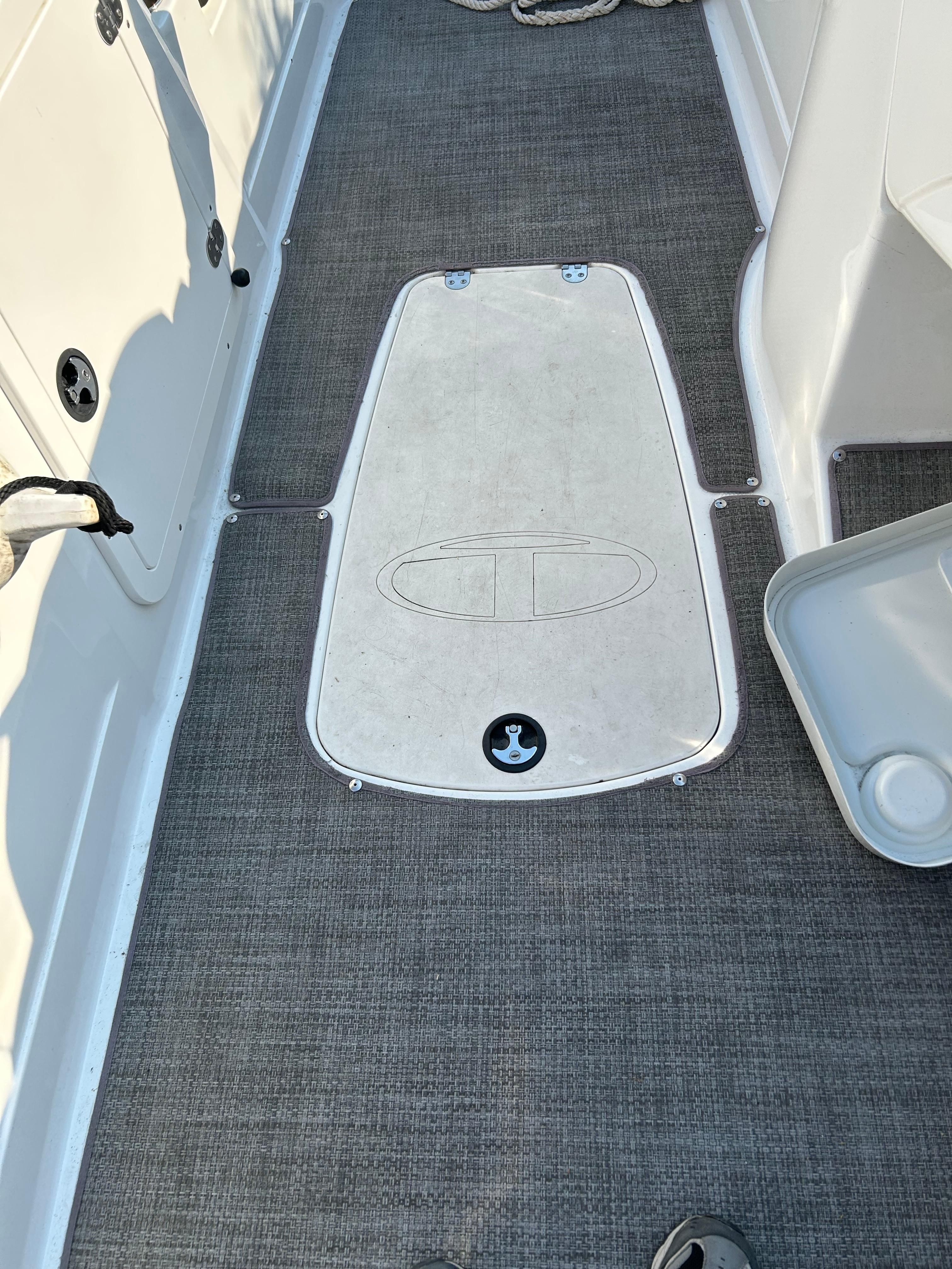 Interior view of a boat with gray carpet flooring and a white hatch cover.