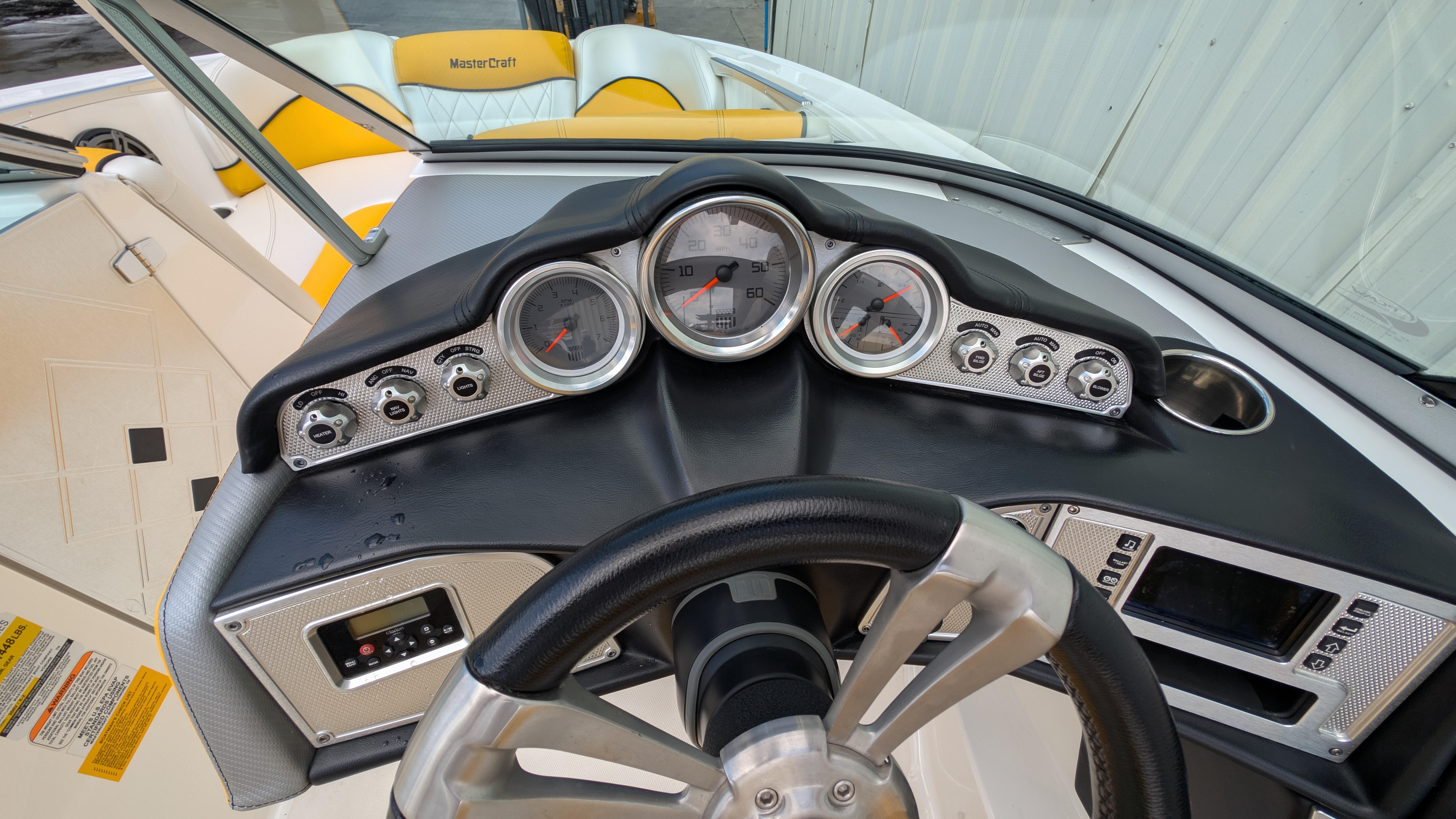 2013 MasterCraft X2 boat dashboard with gauges and steering wheel, featuring yellow seating.