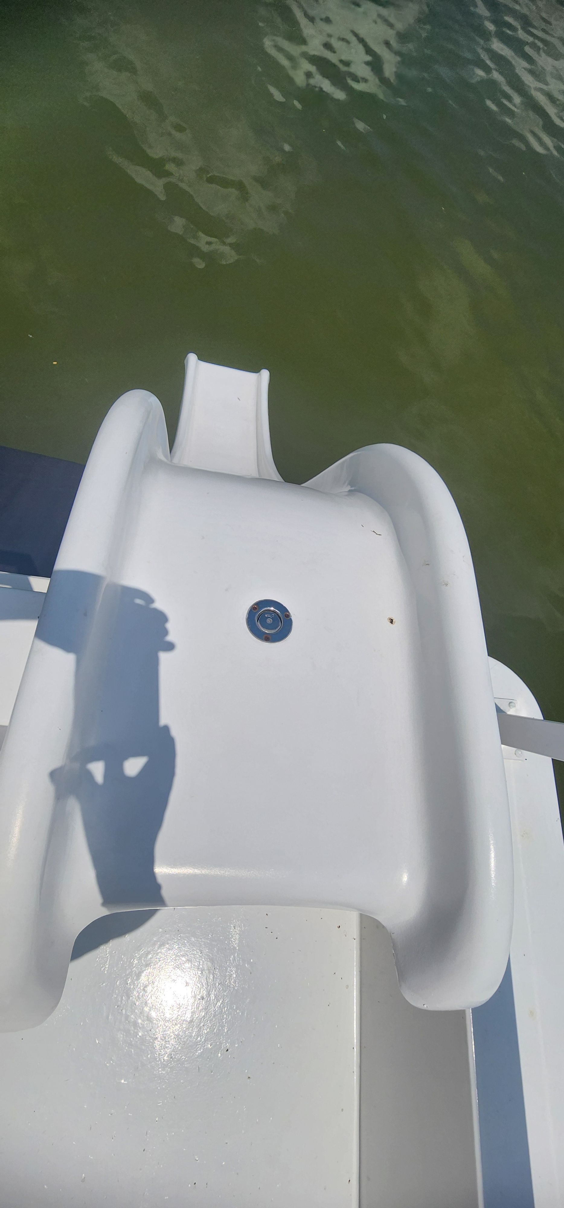 A white water slide on a boat, floating on calm water.