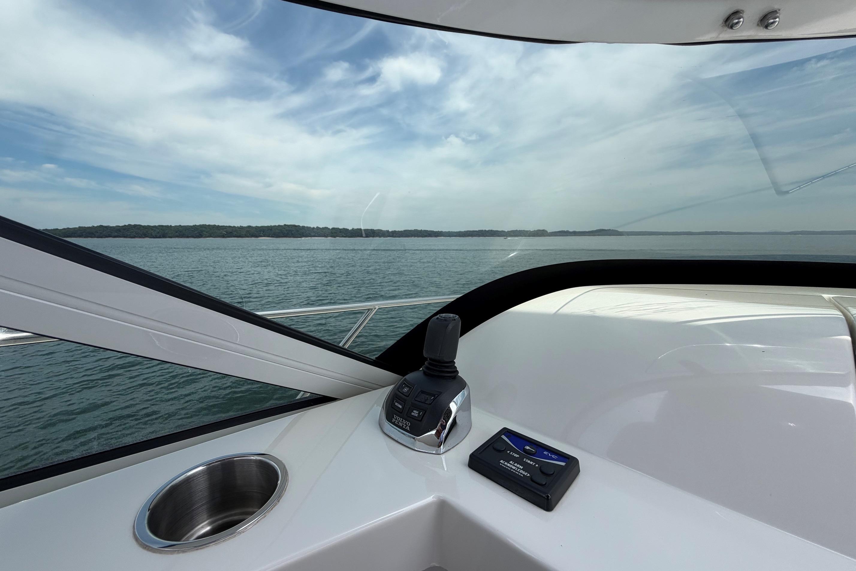 Cockpit view from a 2011 Carver 44 Sojourn yacht, overlooking serene waters and distant shoreline.