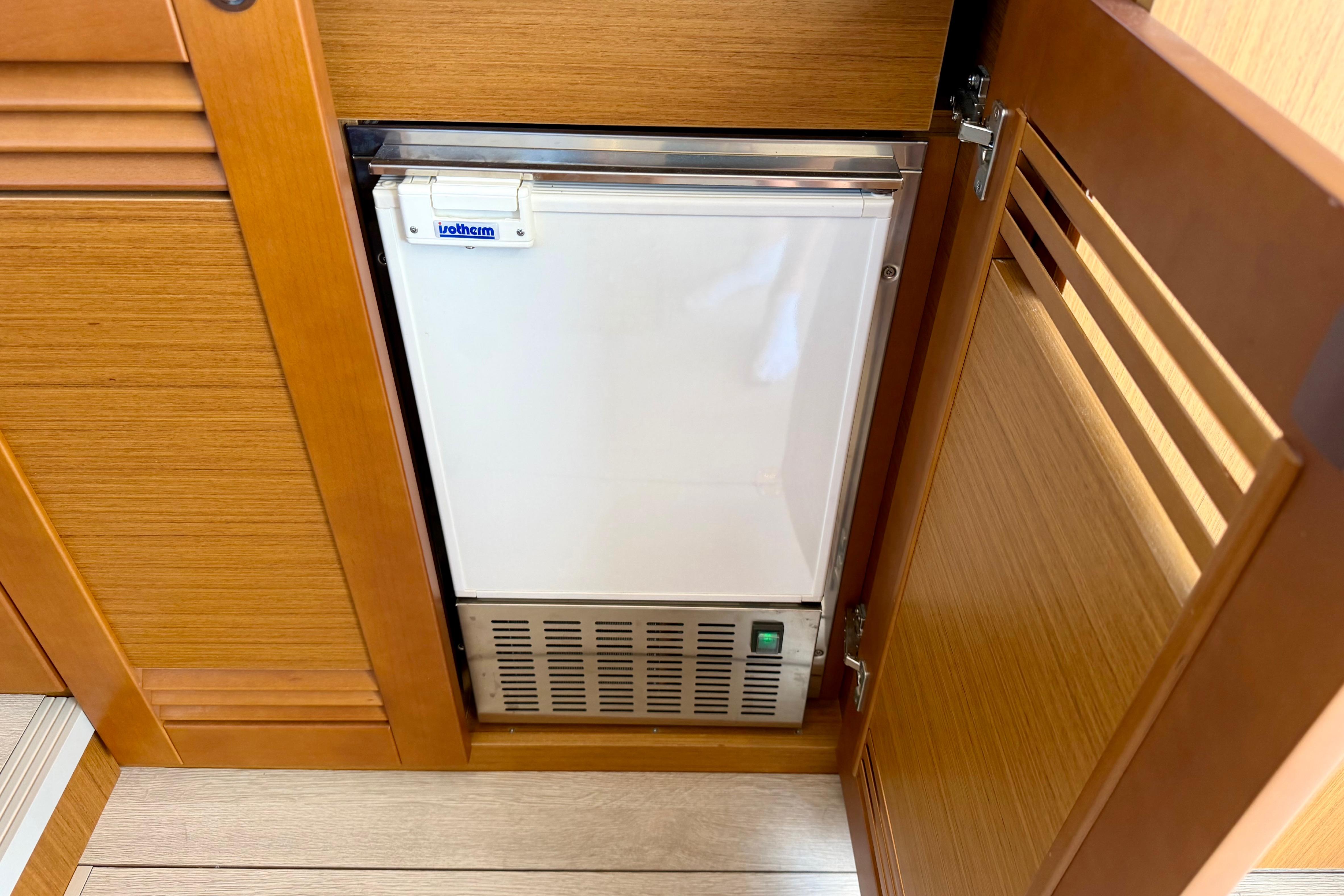 Built-in refrigerator on 2025 Beneteau Swift Trawler 41 Fly, wooden cabinetry.