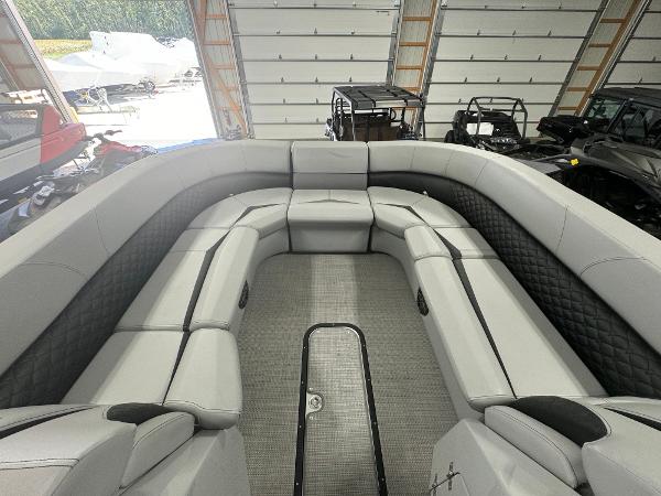 2025 Manitou LX boat interior with spacious seating in a garage setting.